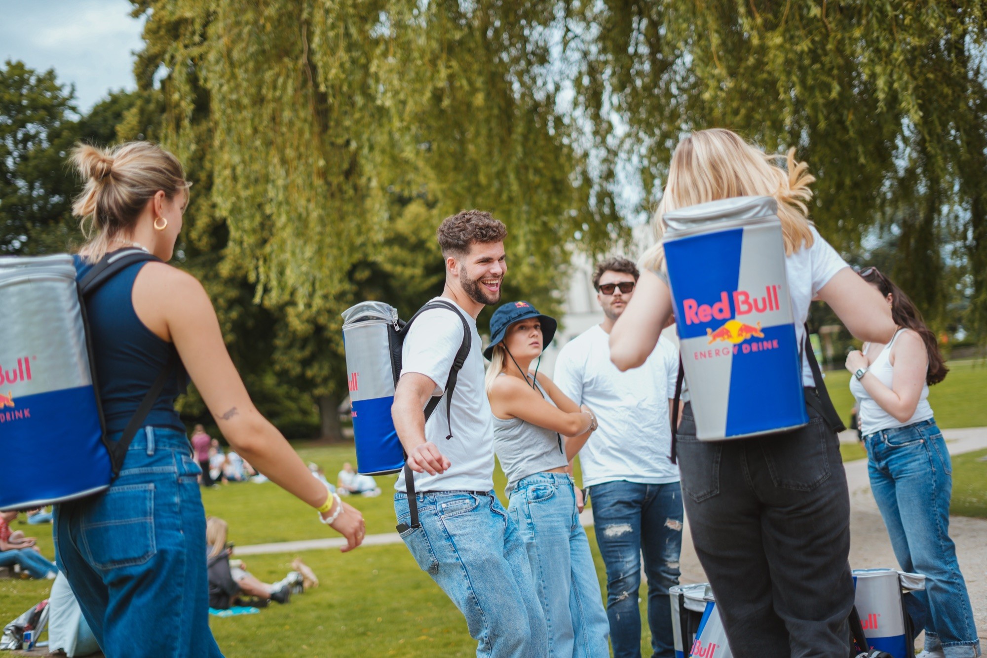 Besucher mit Red-Bull-Rucksäcken auf einer Wiese beim Campus Festival