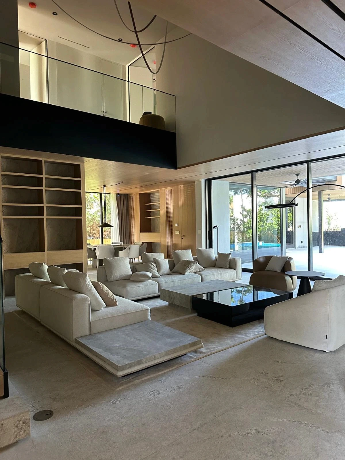 Double-height living space at the Meridian Avenue Residence in Miami Beach by Atelier International, with mezzanine above and sliding glass doors to the pool terrace.