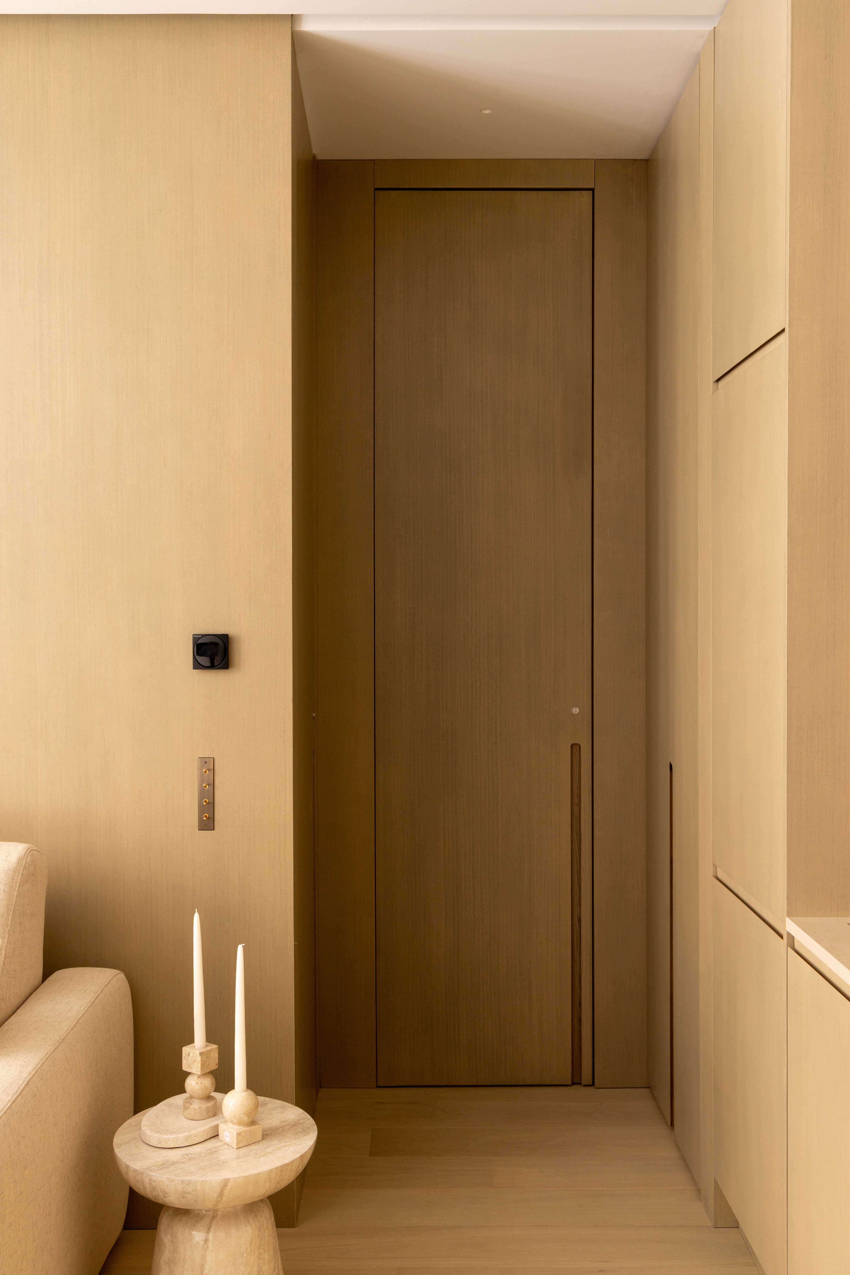 Couloir d'entrée avec porte en bois clair et bougeoirs décoratifs sur guéridon