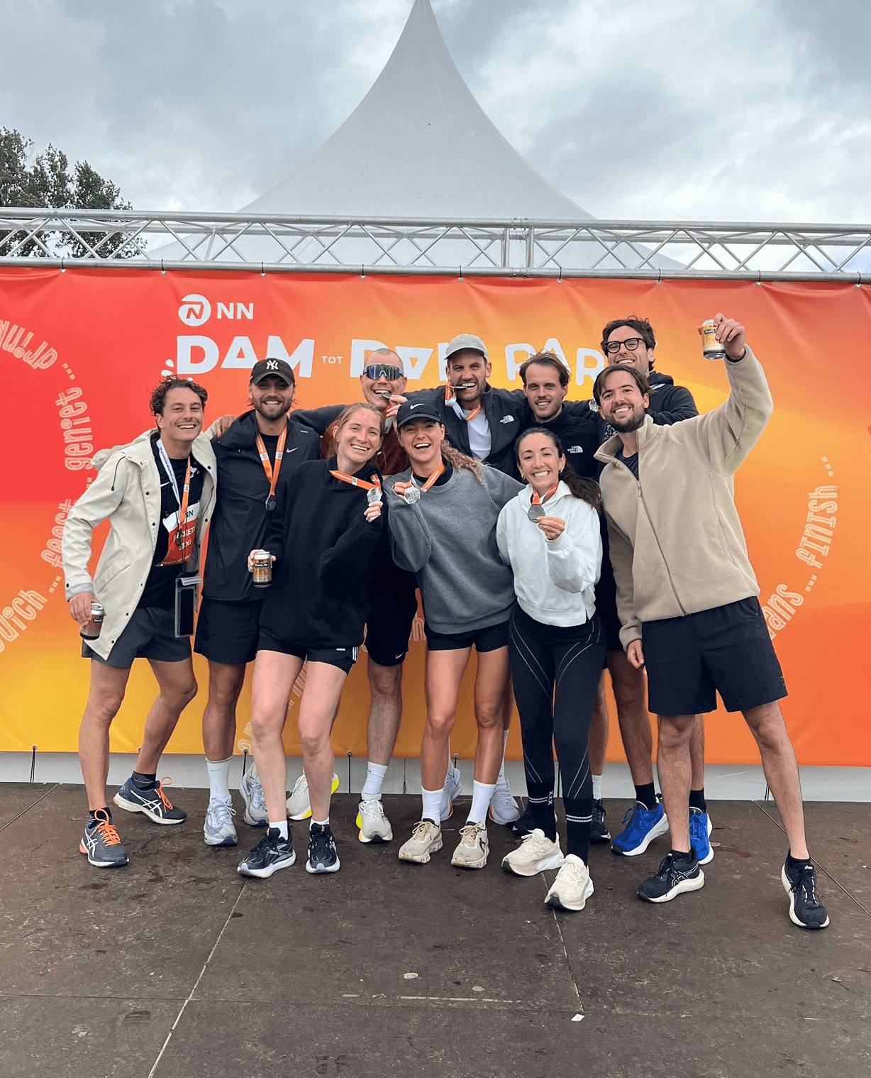 A group of ten people posing together, smiling and celebrating, against a colorful background.