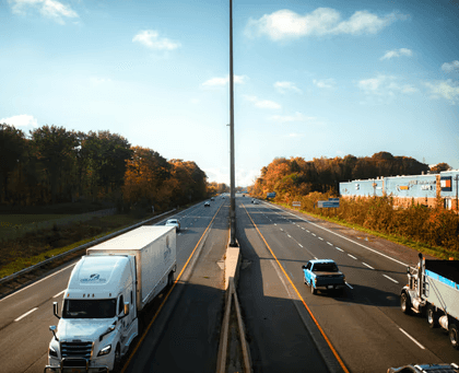 a highway filled with lots of traffic next to a forest