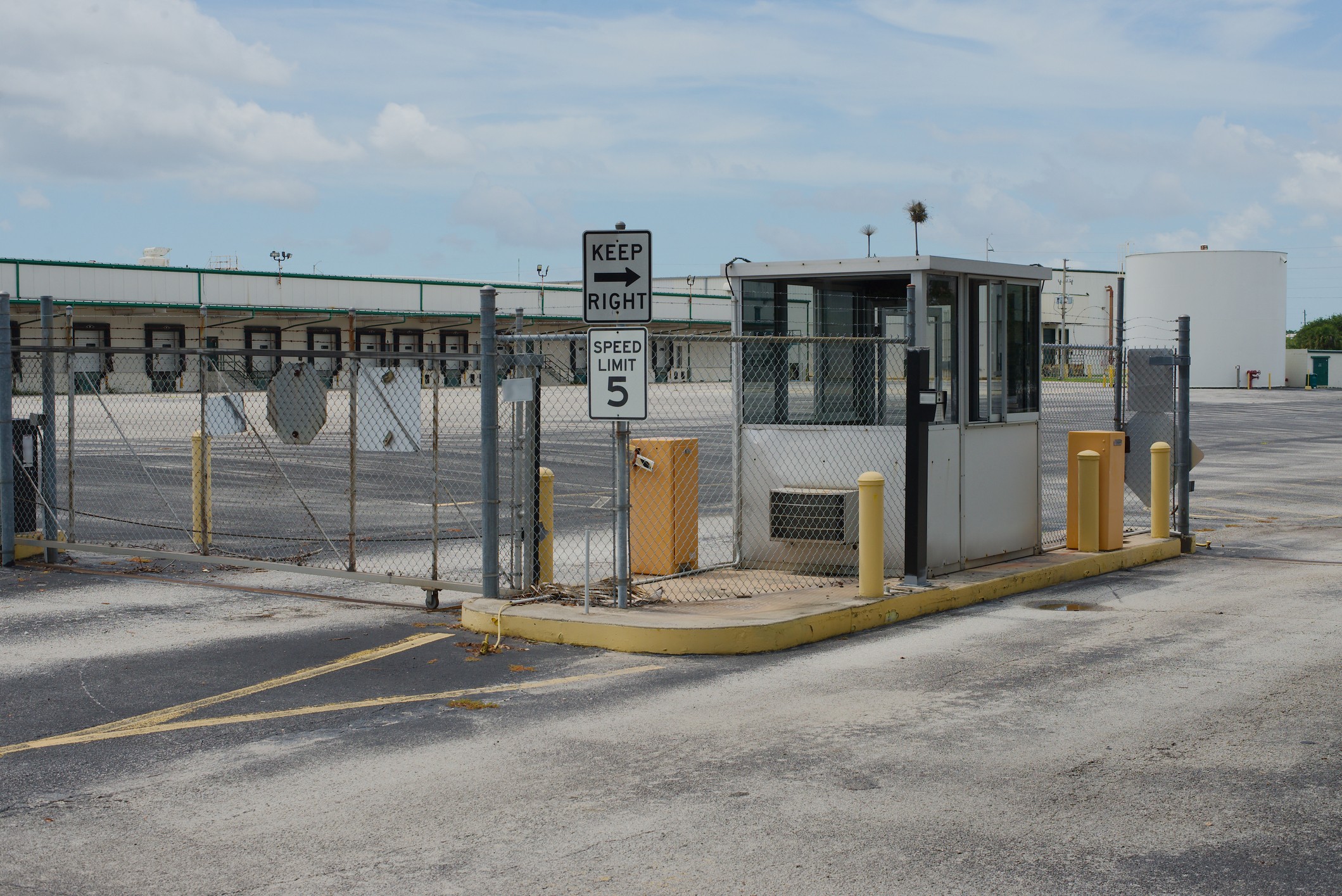 Gated, fenced entrance and guard booth controlling vehicle access to a 3PL warehouse yard and loading docks