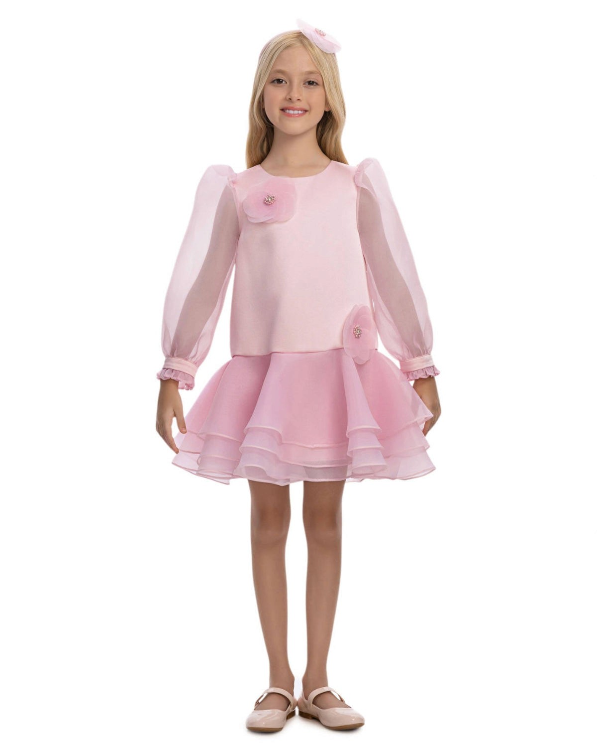 Young girl wearing a pink dress with sheer sleeves on a white background