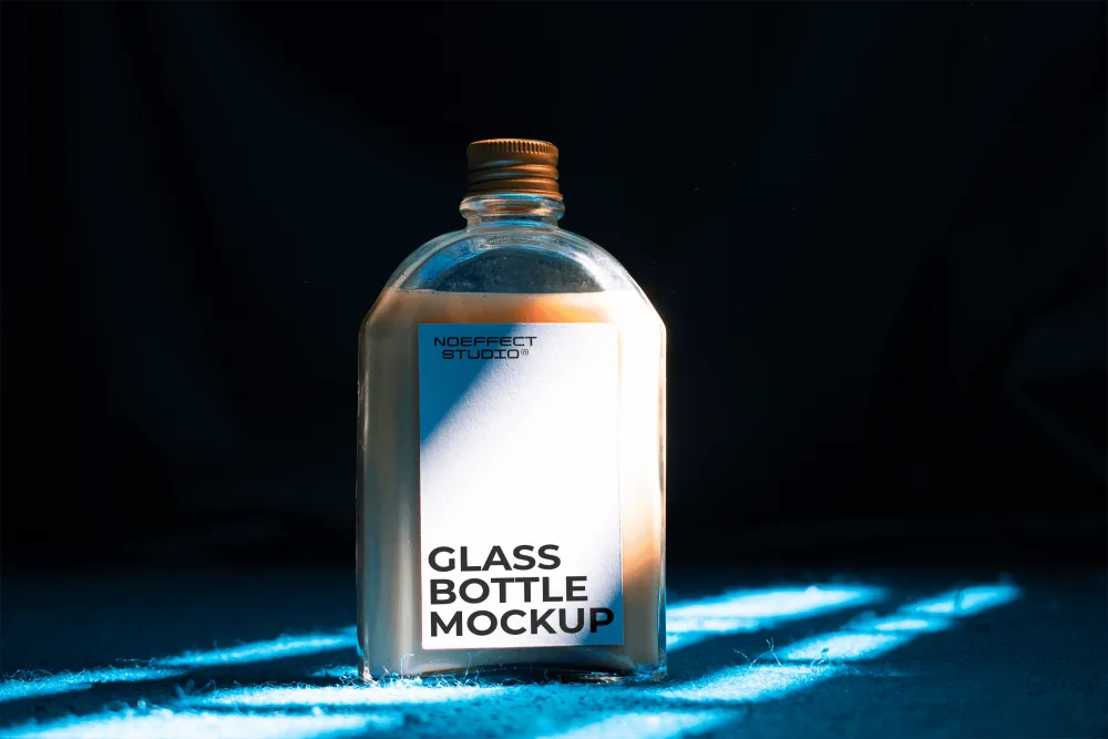 Minimalist glass bottle mockup with a golden cap, illuminated by dramatic blue and orange lighting on a textured surface. The scene features a dark backdrop, emphasizing the product's design.