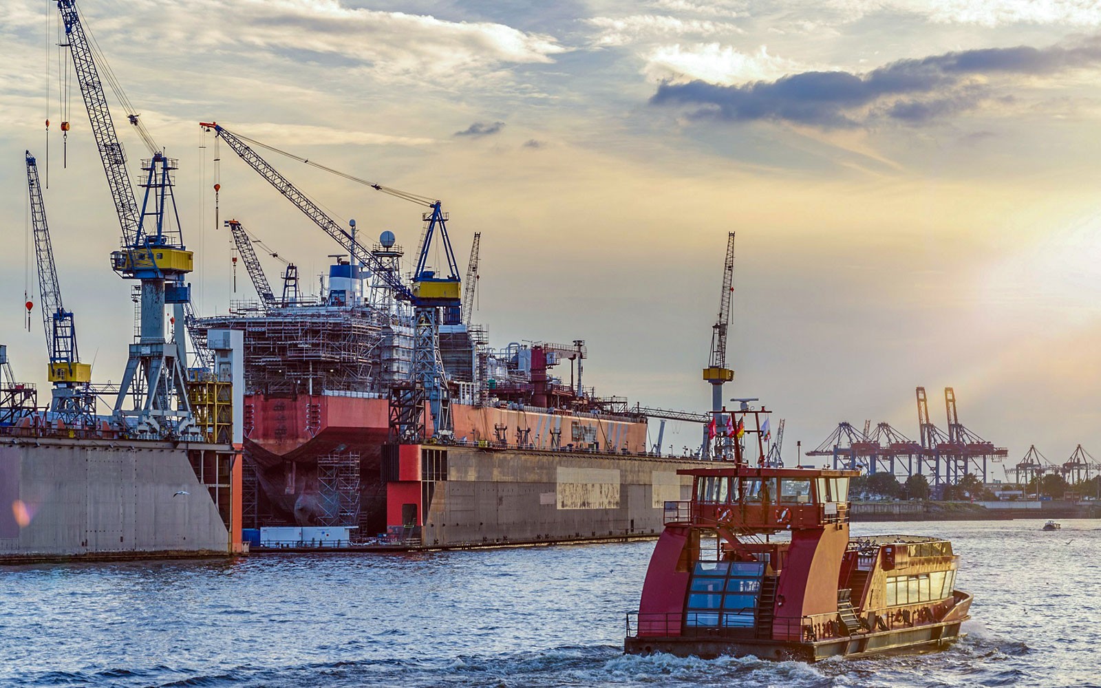 Havnebåd der passerer værftskraner under solnedgangen på en 1-times tur med live kommentarer.