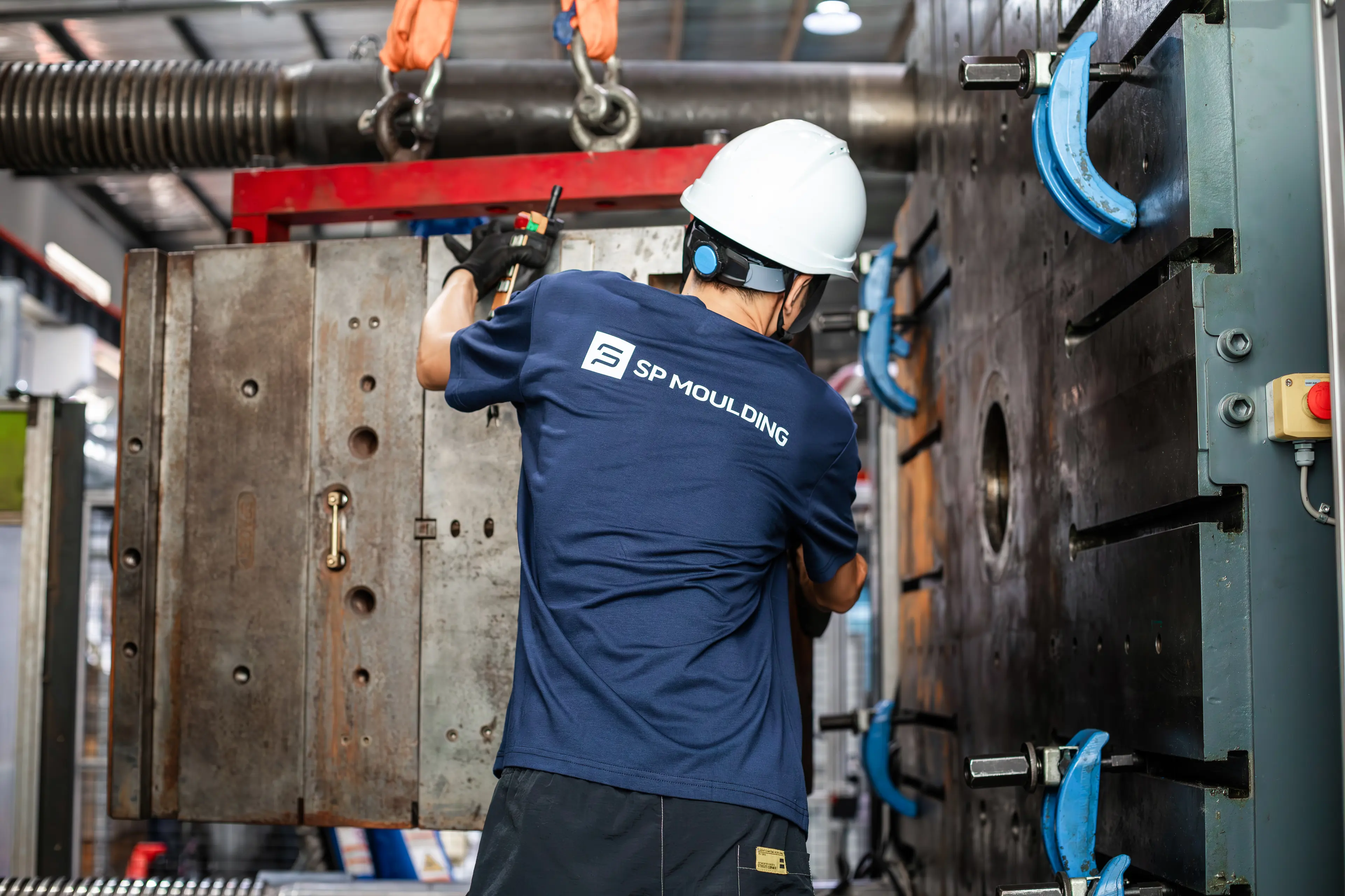 En mand med sikkerhedshjelm laver noget arbejde. Vi kan ikke se hvad han specifikt laver, men noget på en maskine