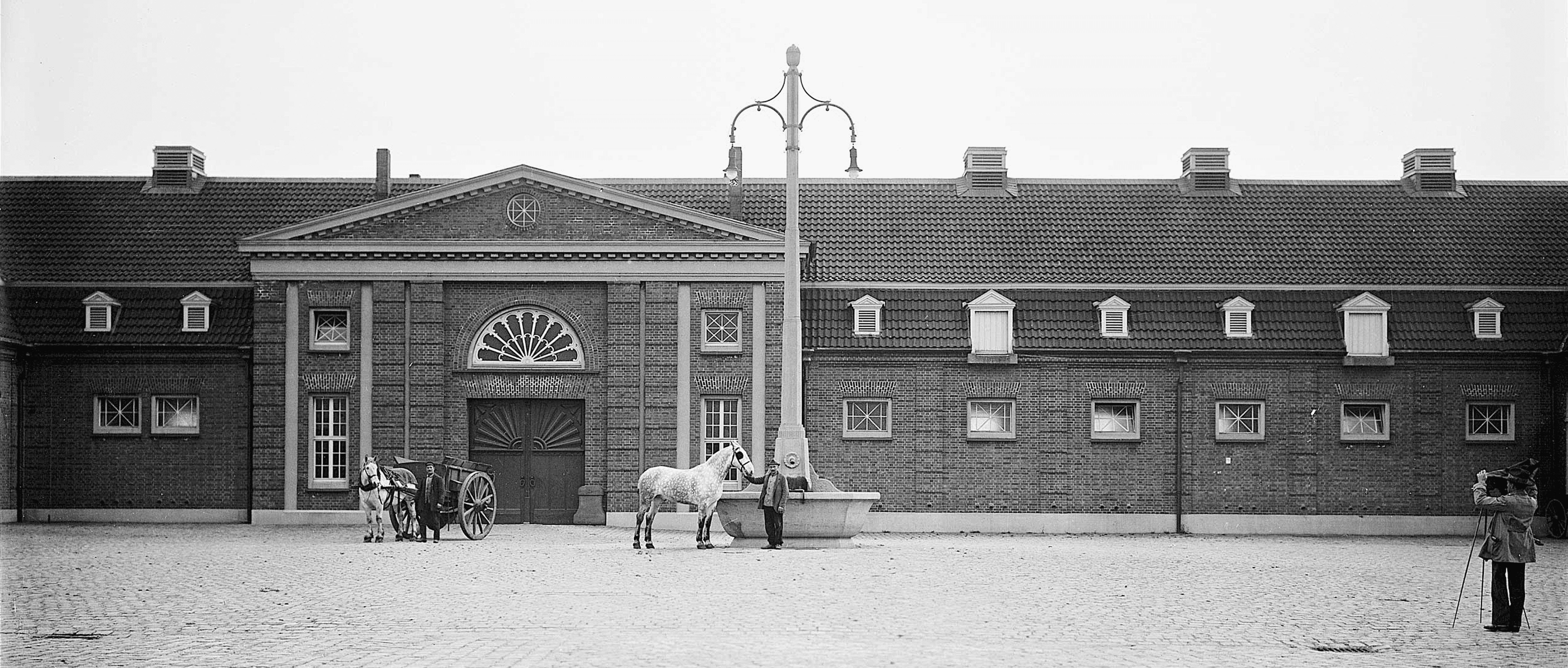Schirrhofgelände in Kamp-Lintfort im Jahr 1923: Ein Pferd steht vor dem Backsteingebäude des ehemaligen Zechengeländes, auf dem heute beim klangrevier festival die Bühne entsteht.