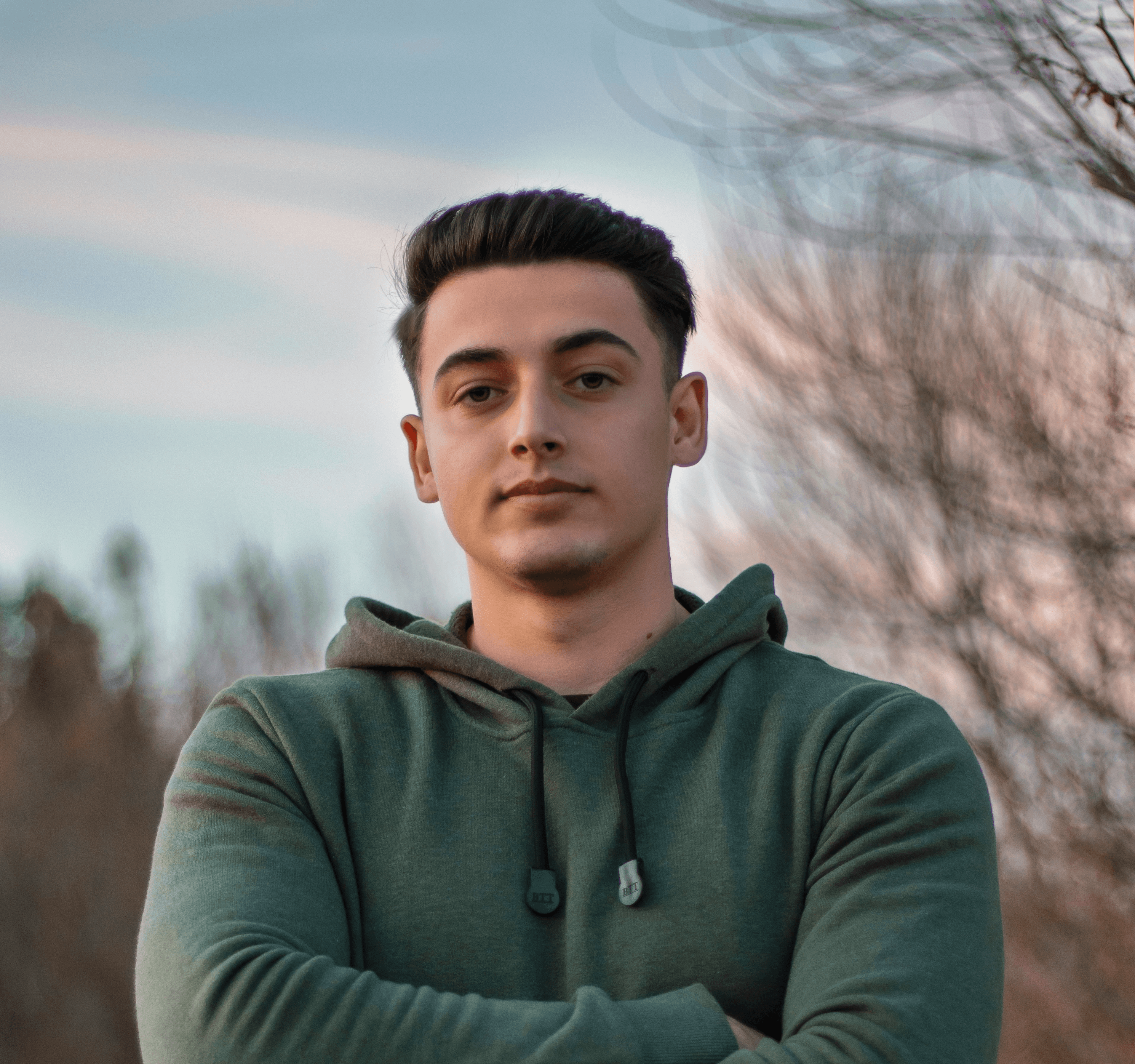 man in green hoodie standing on blue metal railings during daytime