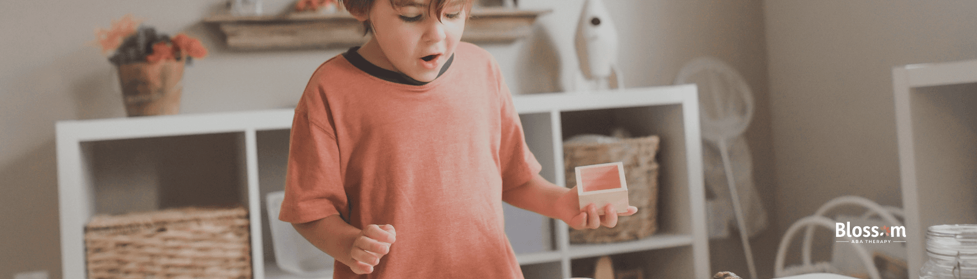 An autistic boy exploring sensory materials in a playroom with shelves during ABA Therapy in TN.