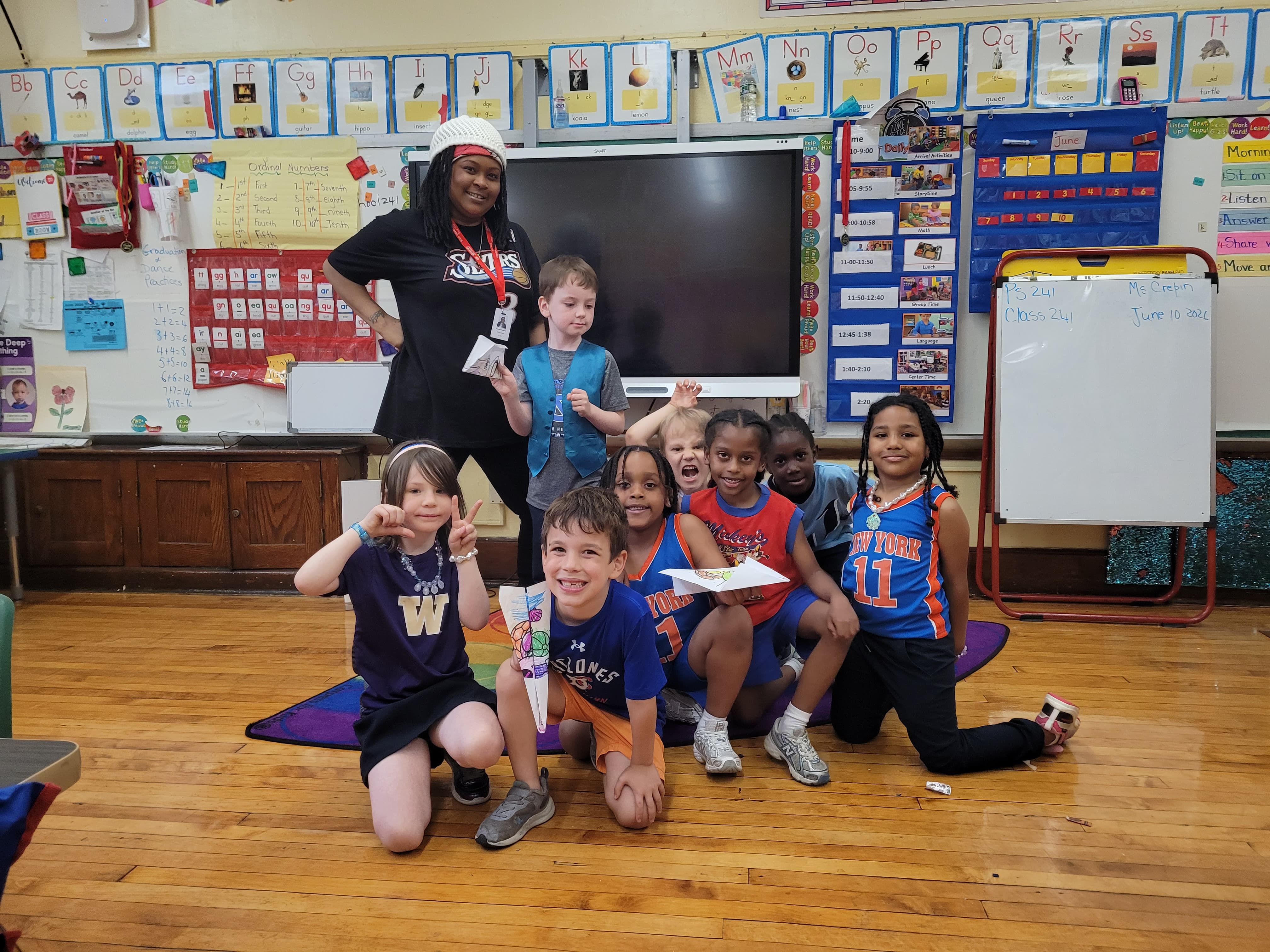 Students pose with their teacher in sport jerseys.