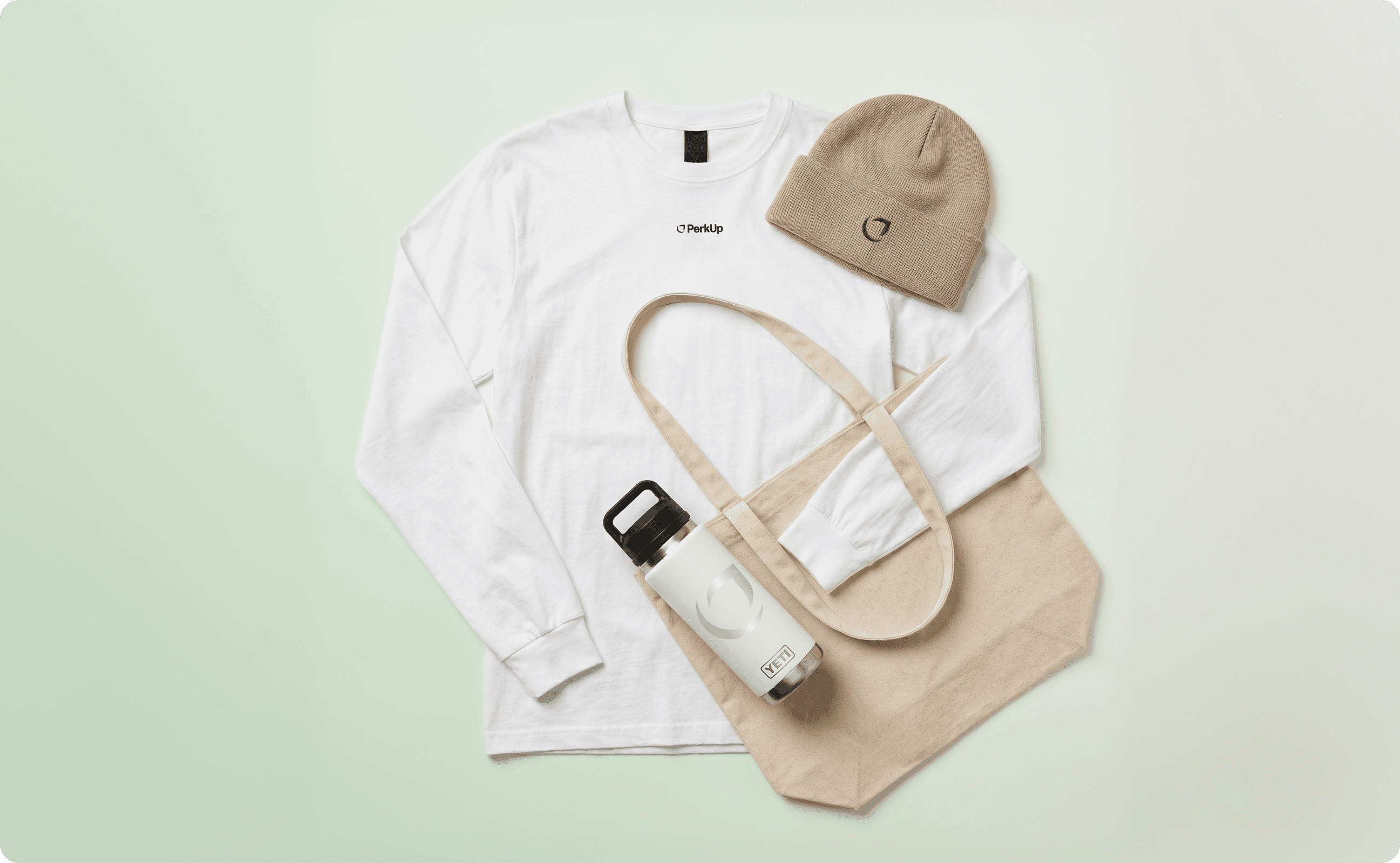 White sweatshirt with a brown beanie, a brown tote bag, and a white YETI tumbler on top.