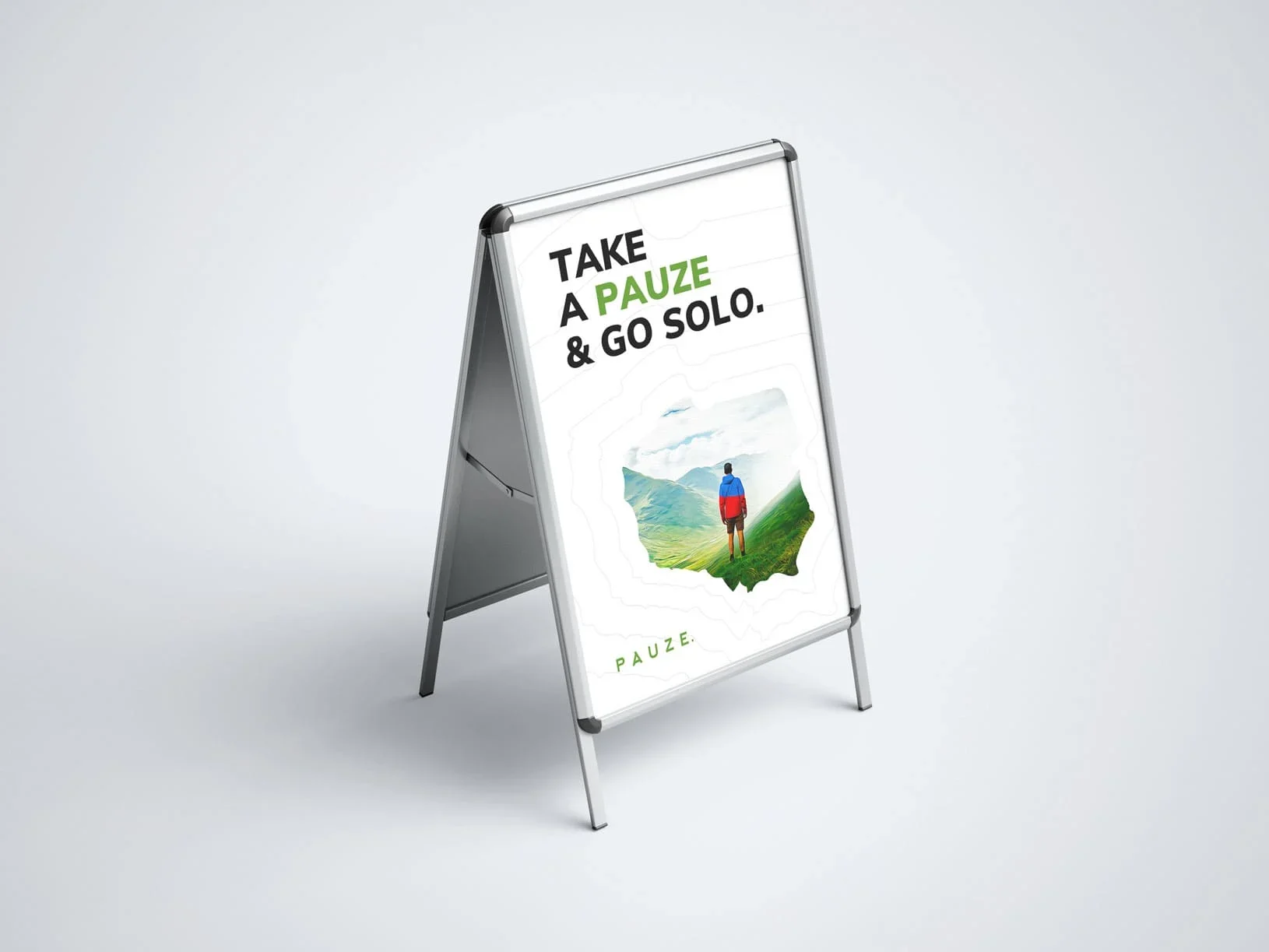 A freestanding sidewalk sign reads “TAKE A PAUZE & GO SOLO,” showing a lone hiker in a green landscape; calm, encouraging outdoor travel message.