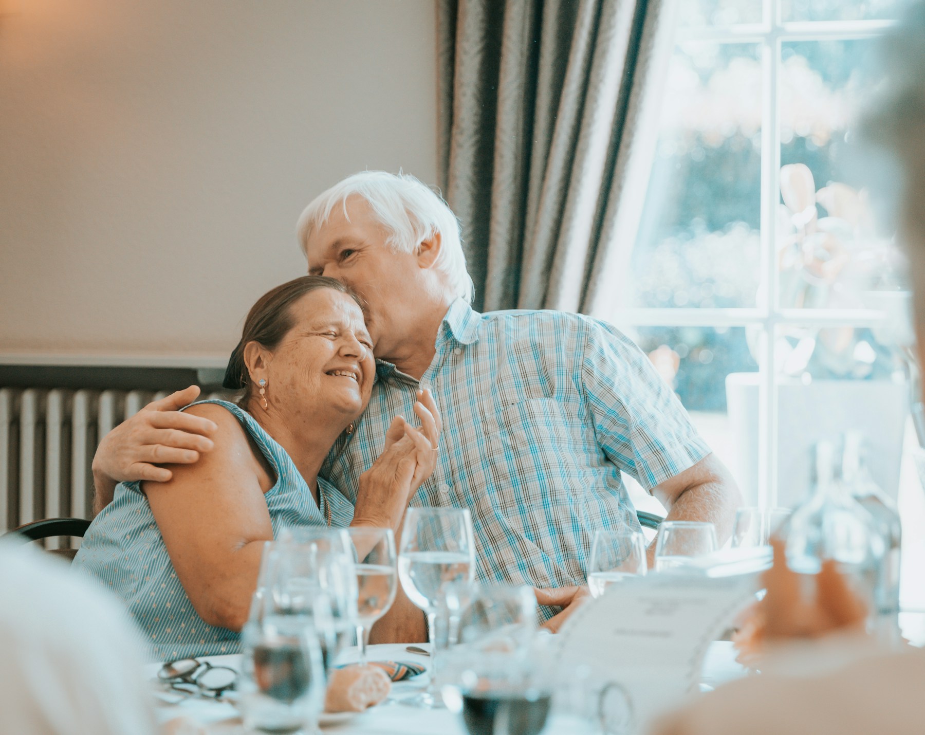 An older couple sharing a warm moment at a set dining table