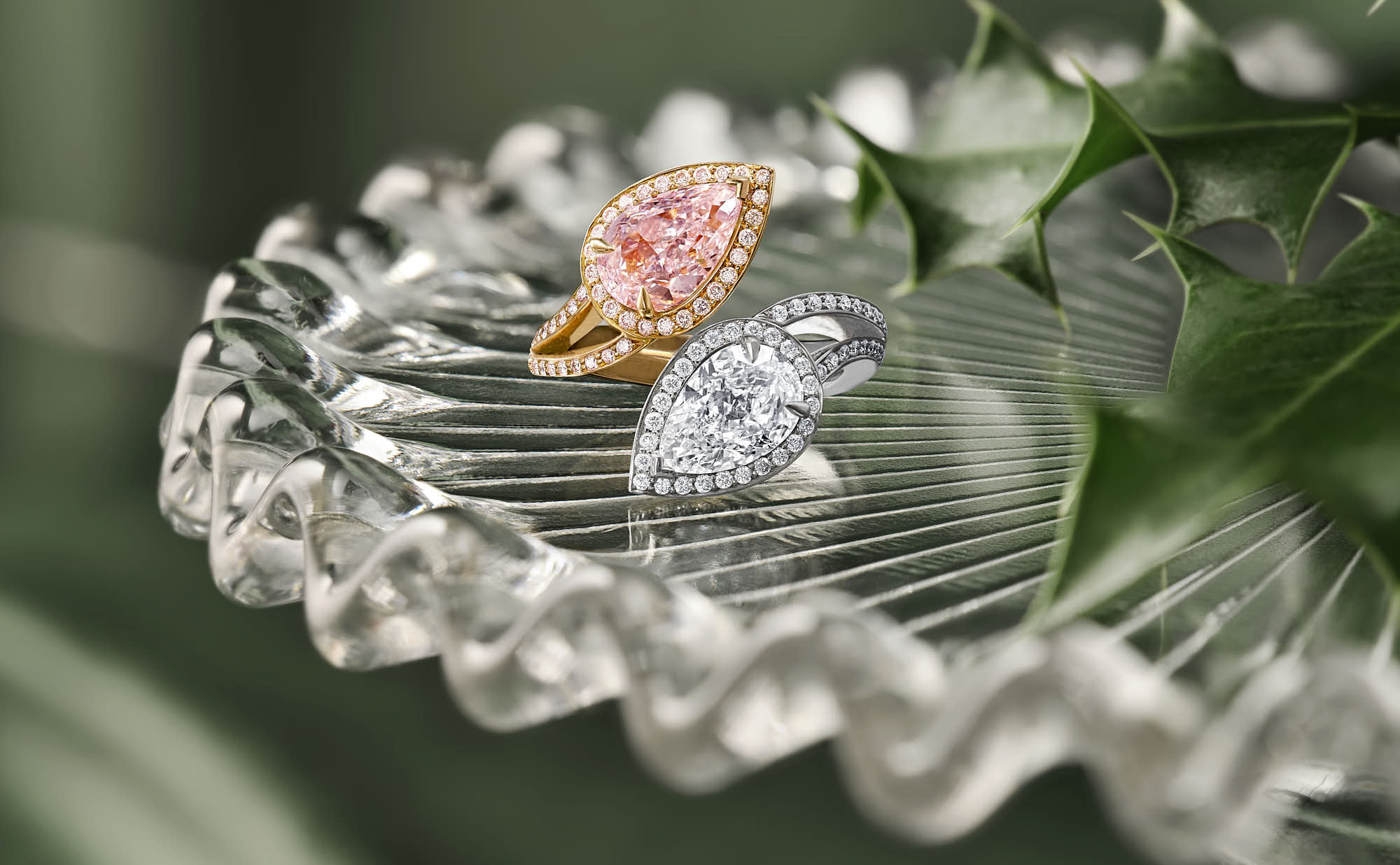 Delicate glass dish with a floral arrangement, featuring a boodles rose gold and platinum ring and greenery, set on a blurred background.