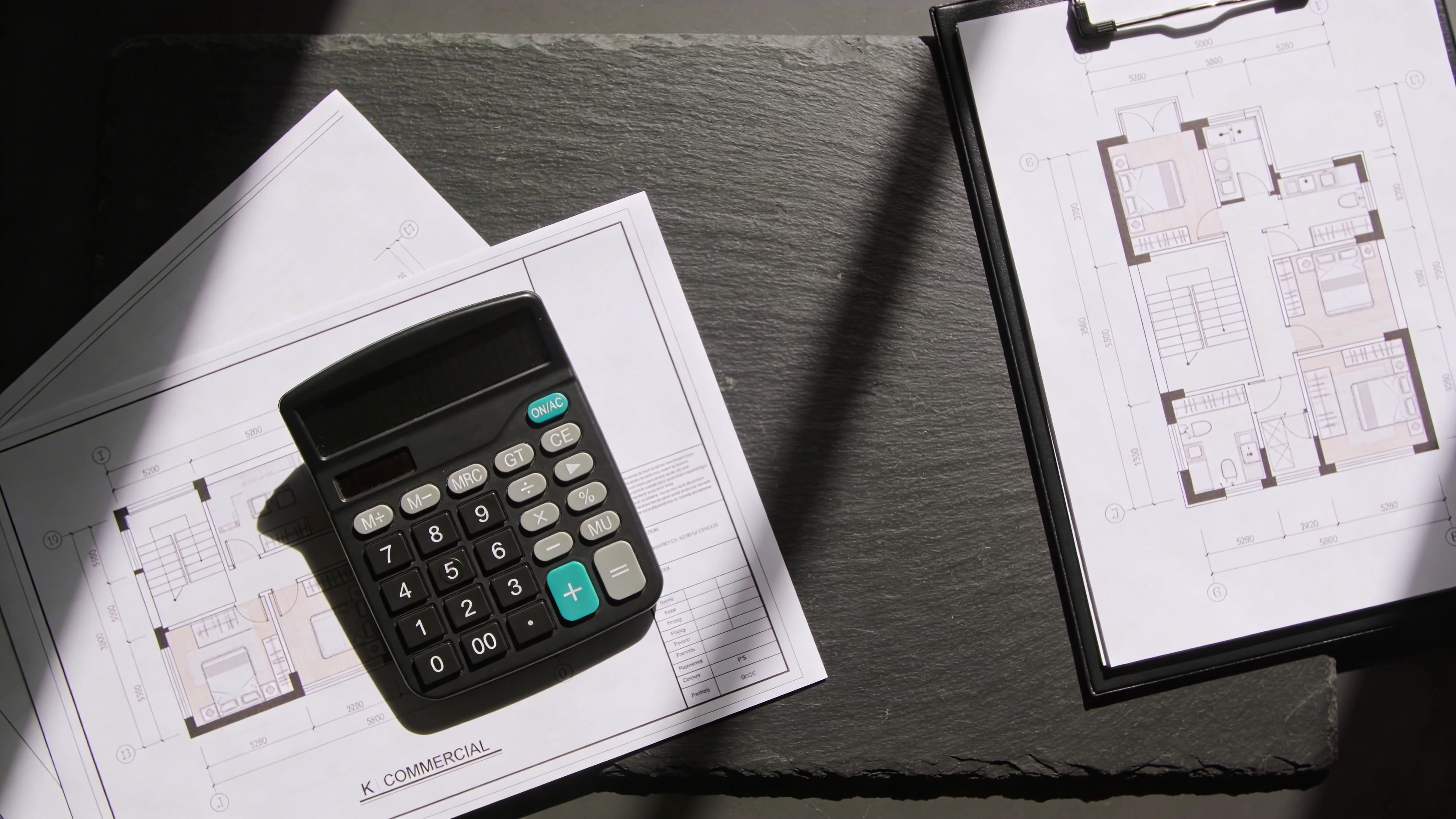Real estate floor plans with a calculator on top for property cost estimation