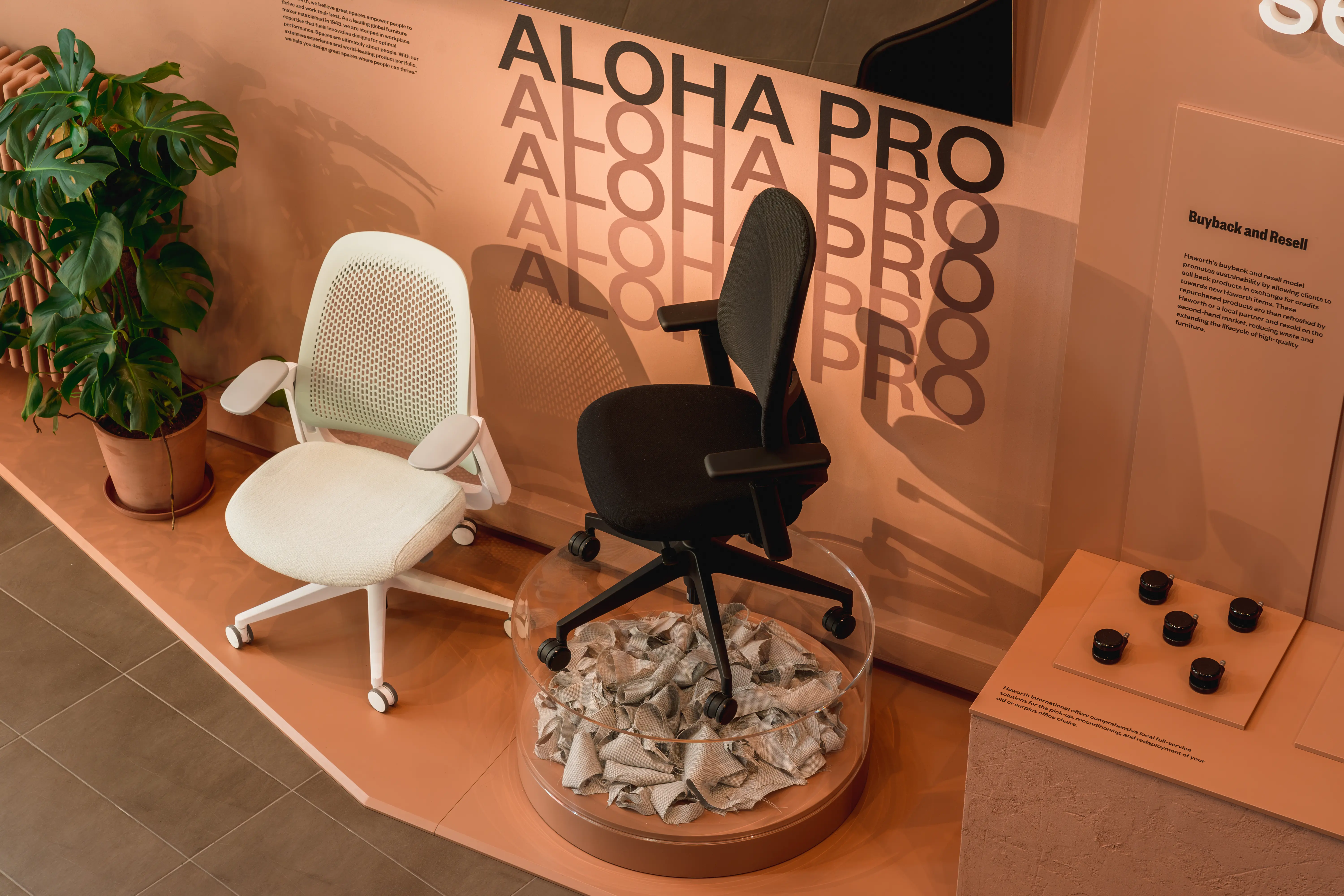 Aloha Pro office chairs in cream and black, one on a glass drum filled with recycled material, in the Haworth showroom.