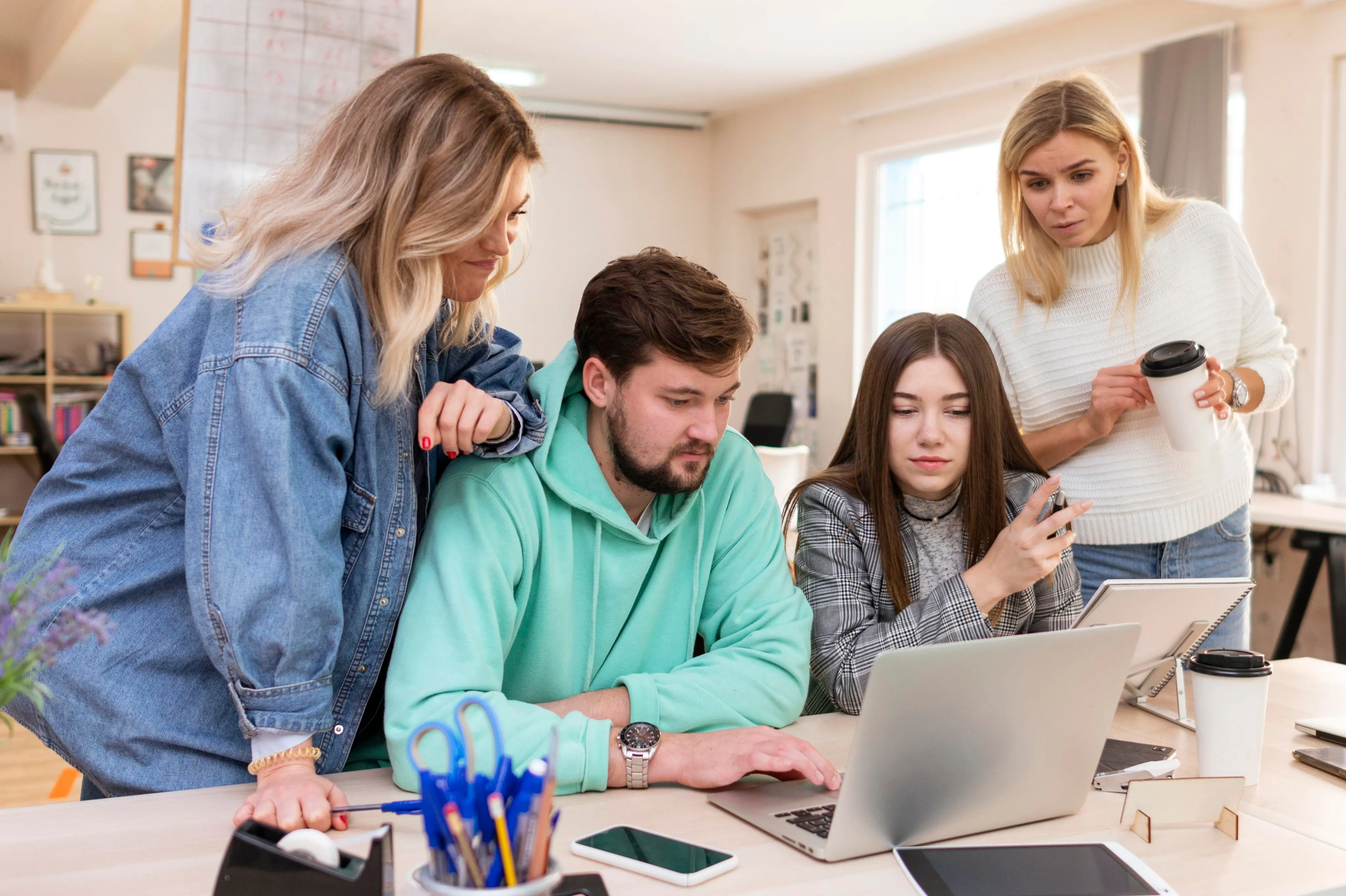 A diverse group of cheerful colleagues laughing and collaborating during a meeting in a bright, modern office space.