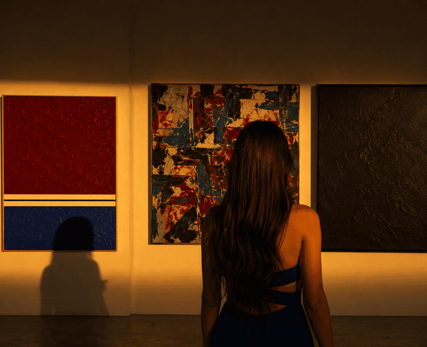Visitors observing a large mural painting depicting industrial and social themes in a modern art gallery