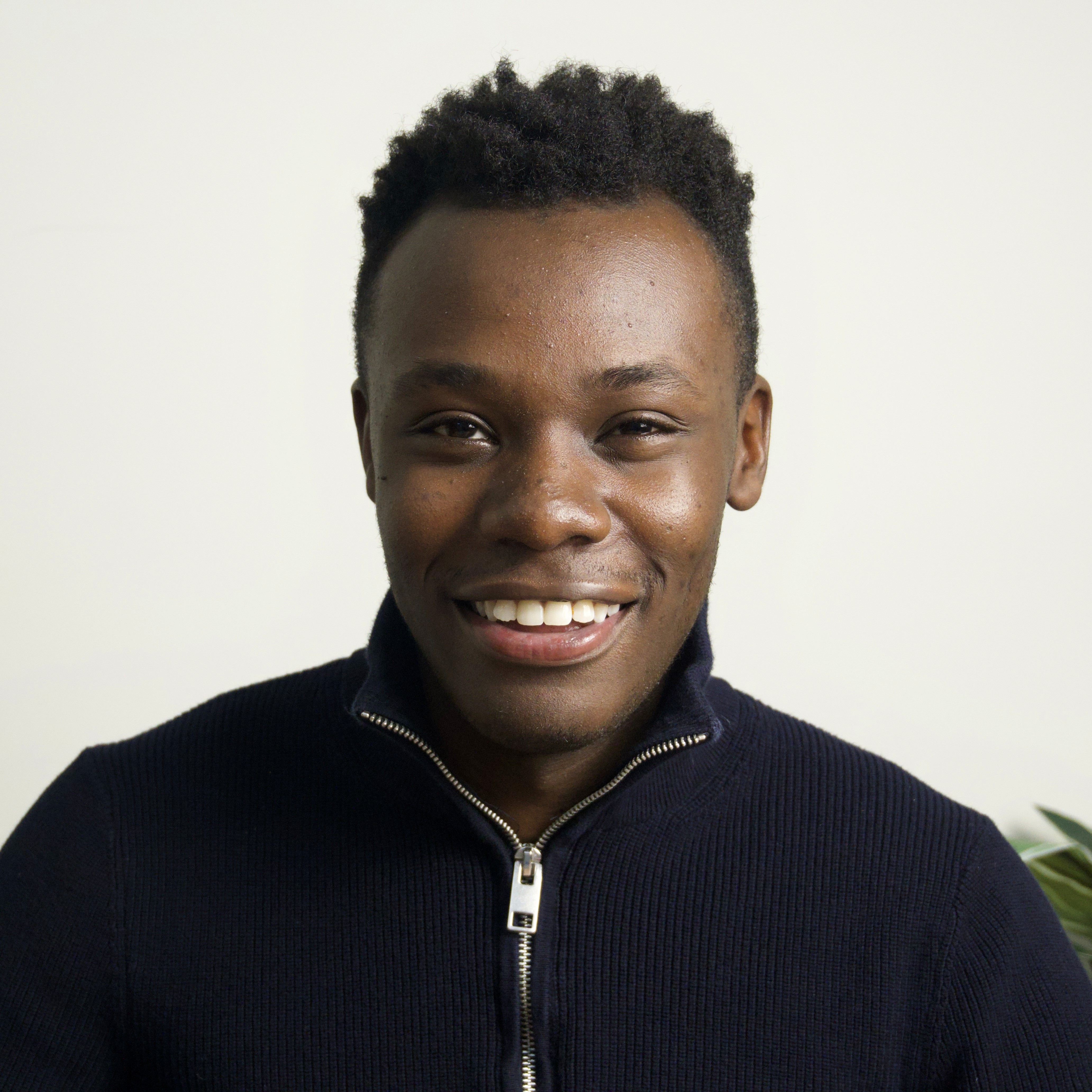 Immanuel sitting in a living room with a couch and painting behind him.