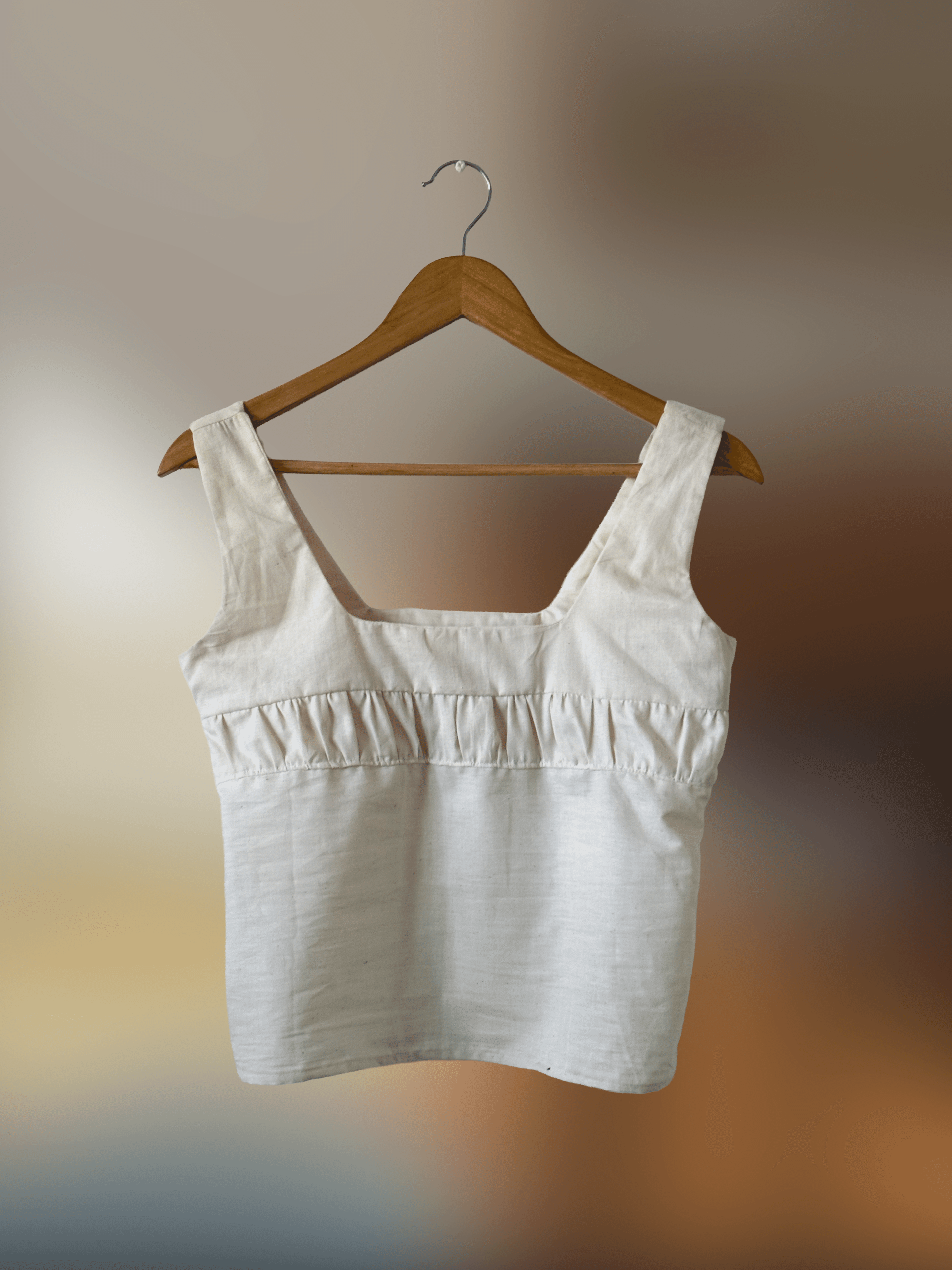Front of a natural cotton top with thick straps and some gathering detail