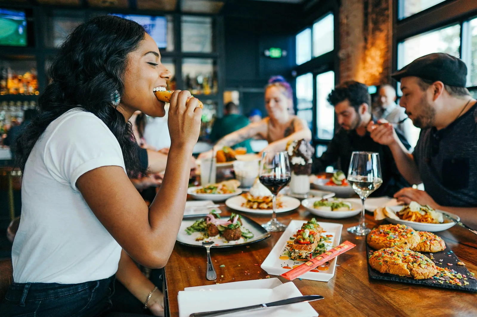Group of diverse diners enjoying appetizers and wine together at a restaurant bar counter.