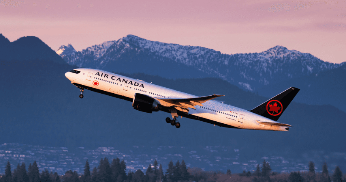 An Air Canada plane flying with mountains in the background