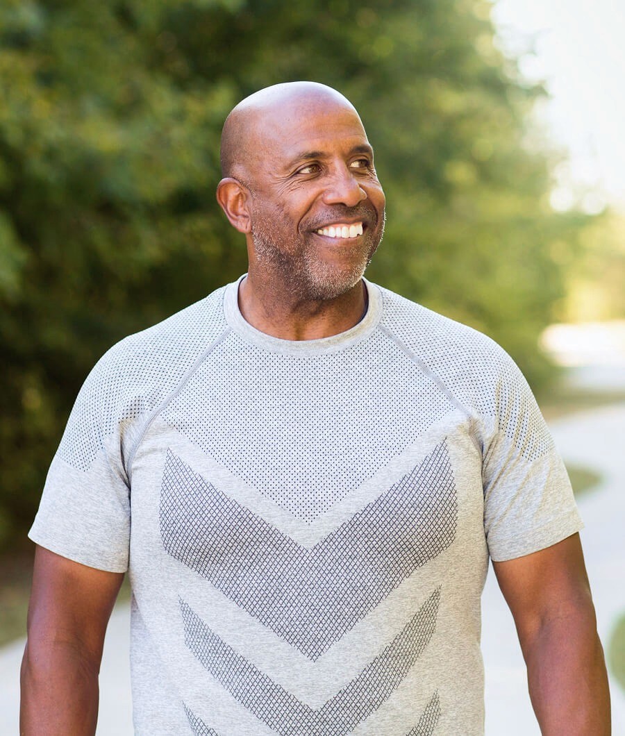 An older Black man with a shaved head smiles looking right.