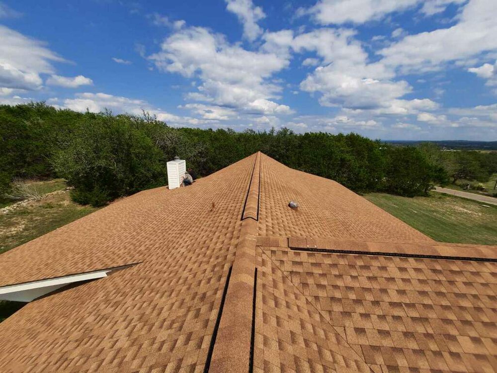 Desert Tan Owens Corning architectural shingle roof with a chimney and ridge vent.