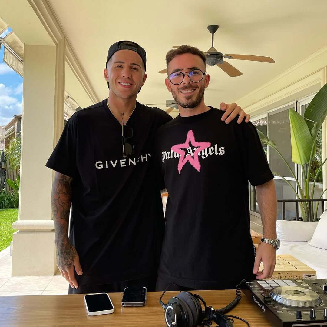 Fer Palacio junto a Enzo Fernandez en un asado, ambos con camisetas negras y una consola de DJ cerca.