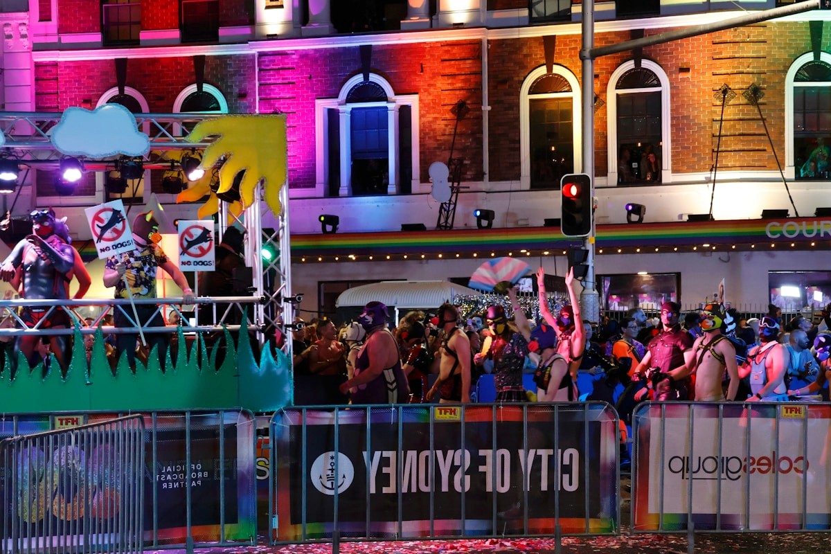 People celebrating at a vibrant night parade with colorful lights.