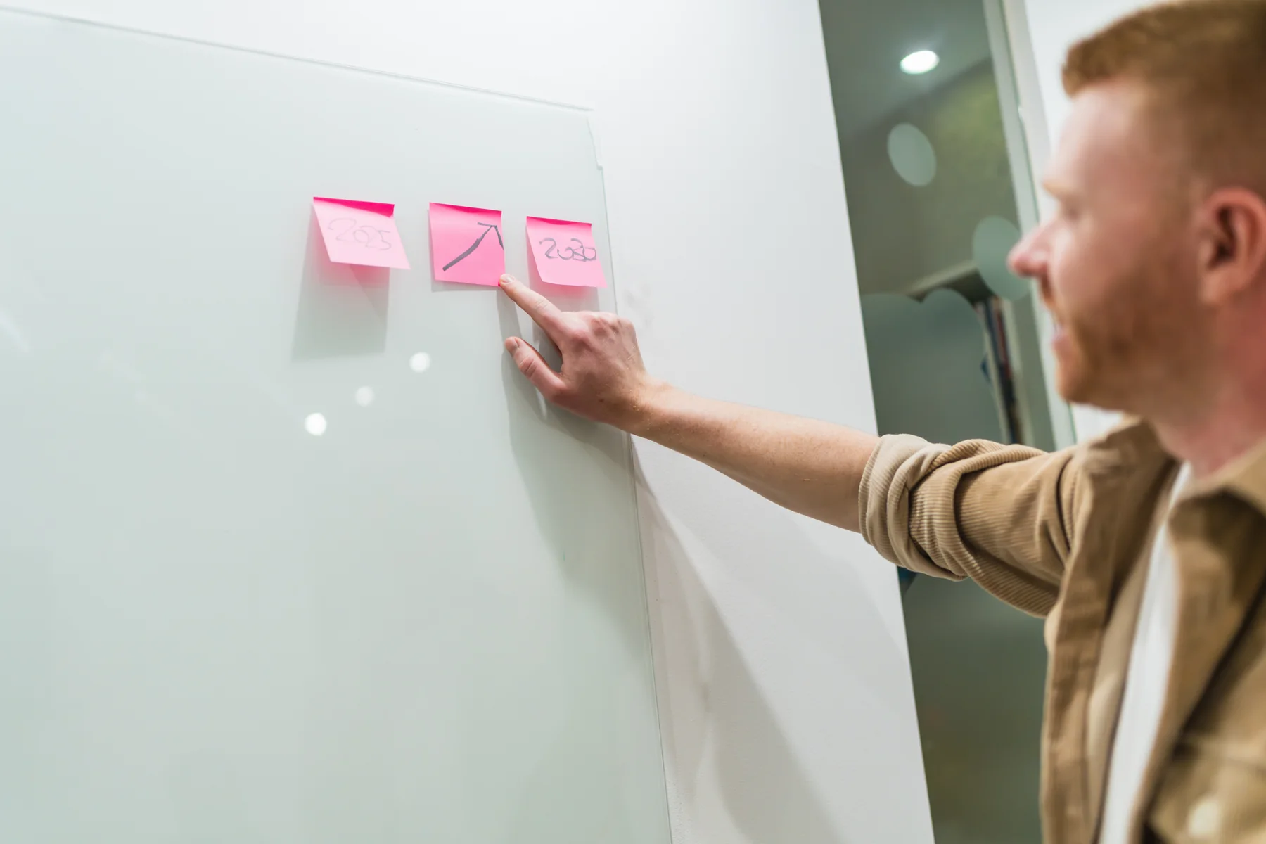 Man Points to Sticky Notes on Whiteboard