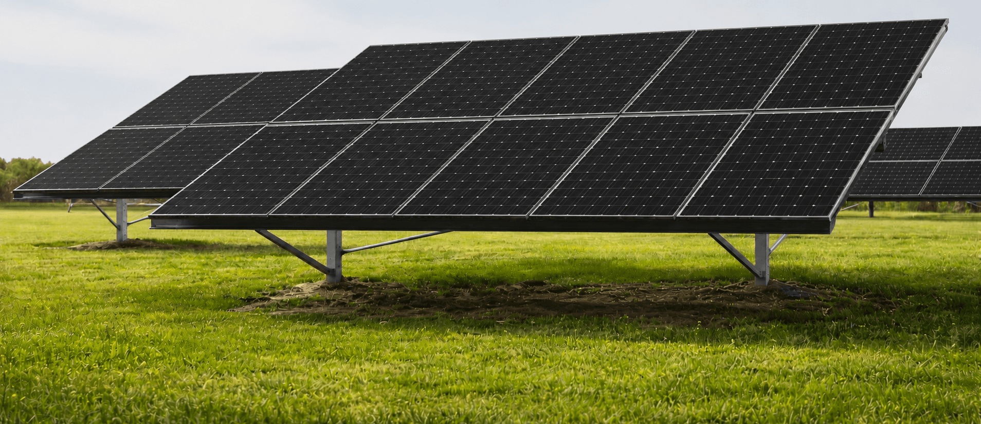 Solar panels on a grassy field under a clear sky.