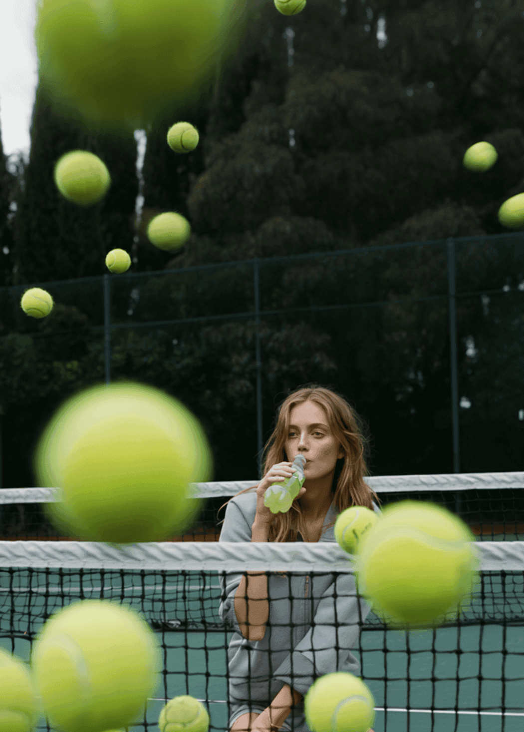 Women sitting drinking a schweppes with tennis balls flying around