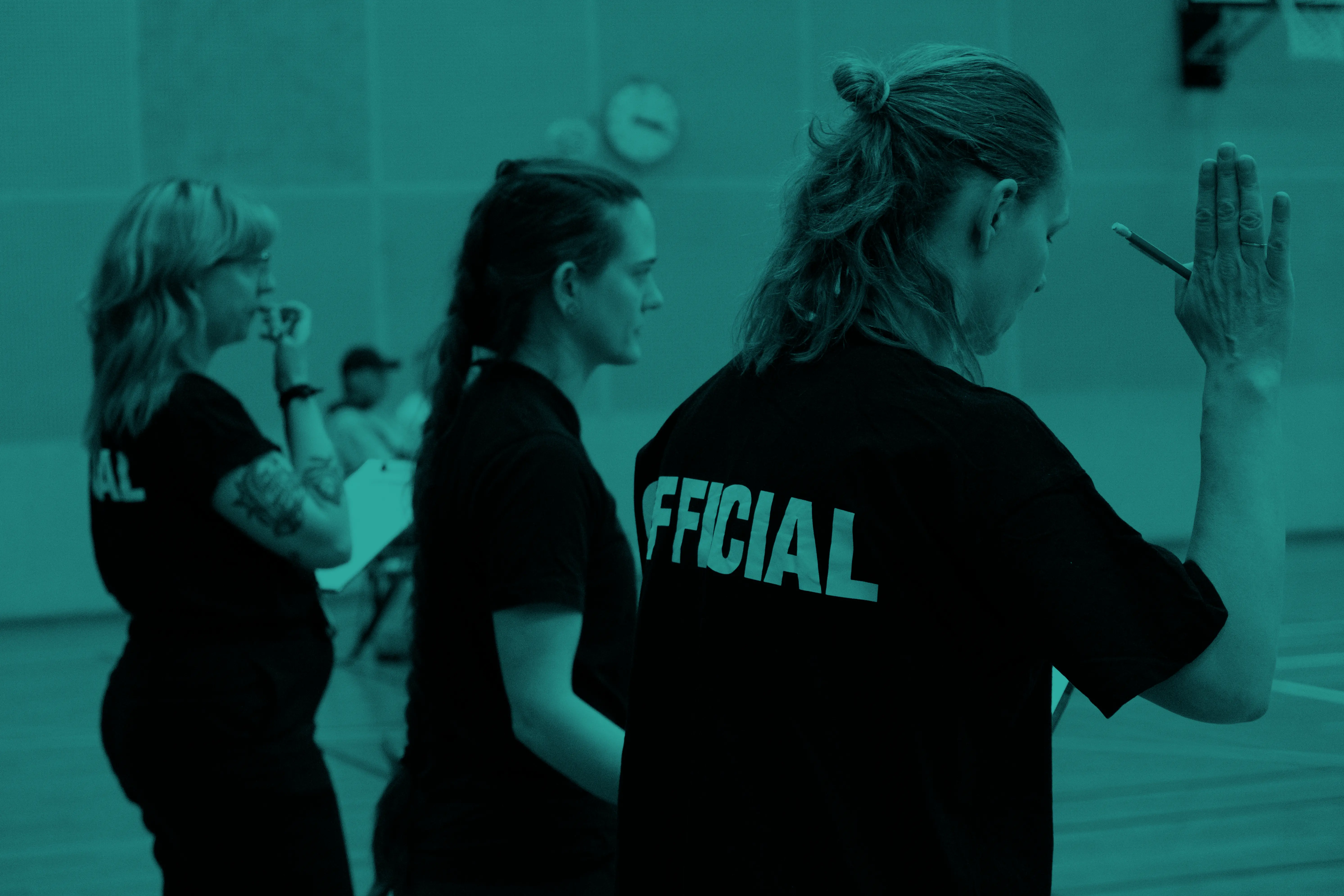 A group of roller derby officials making hand gestures and blowing a whistle.