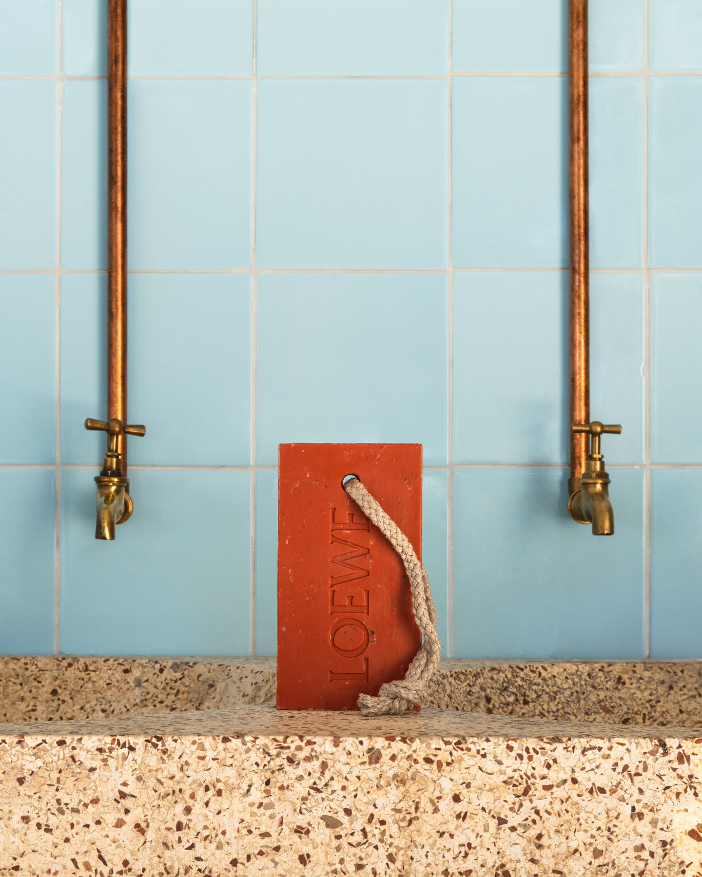 Tomato leaves soap bar photographed against blue tiles in a Mediterranean setting.