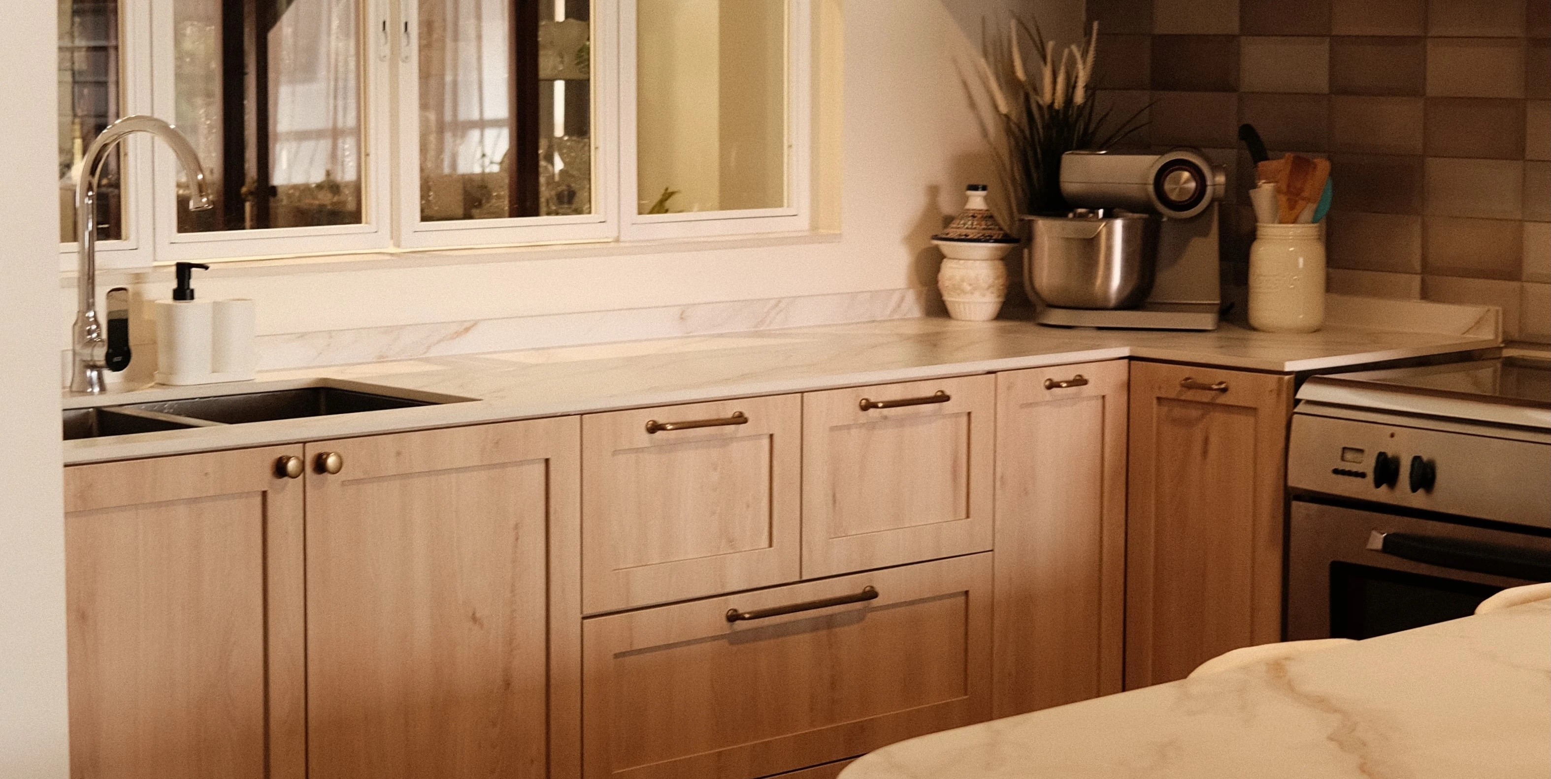 Minimalist kitchen design with white countertops, integrated appliances, and wood accents, HDB interior design Singapore