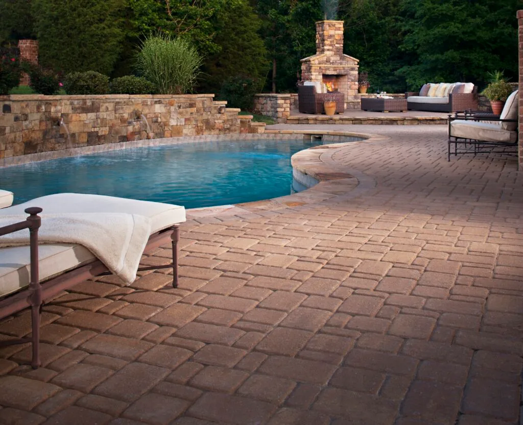 A terrace that follows the pool Warm-toned paver pool deck with lounge seating and an outdoor fireplace.