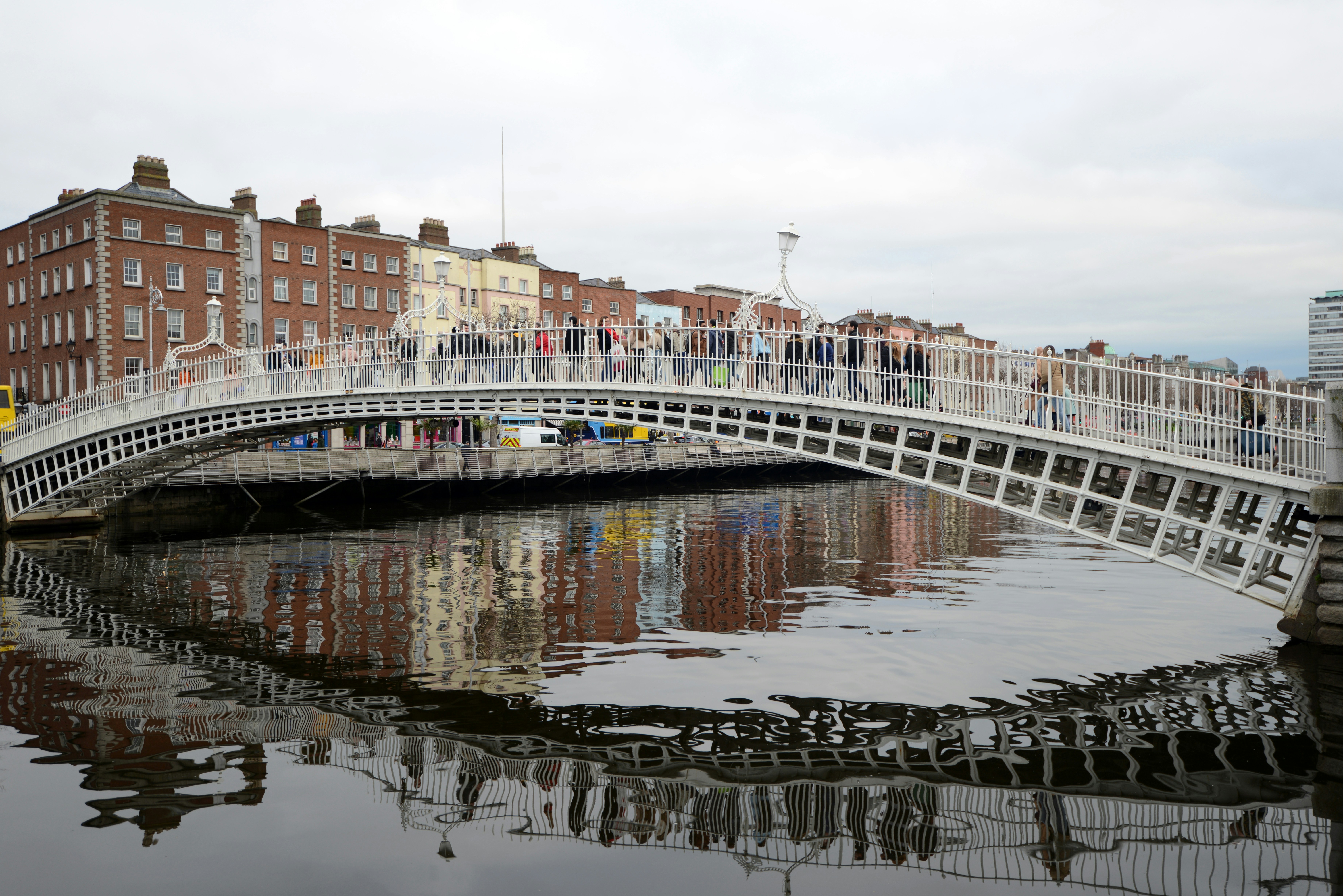 White arched bridge over a river with buildings.