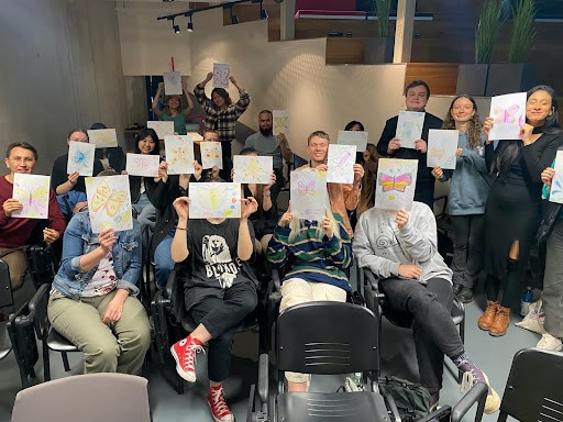 Image taken at our art therapy workshop with a group of students holding their drawings in front of their faces