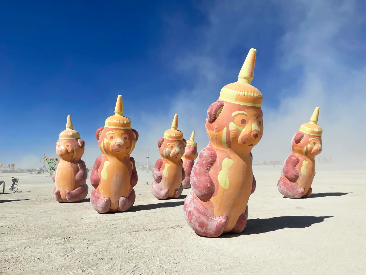Multiple honey bear bottle inflatables in the middle of the desert.