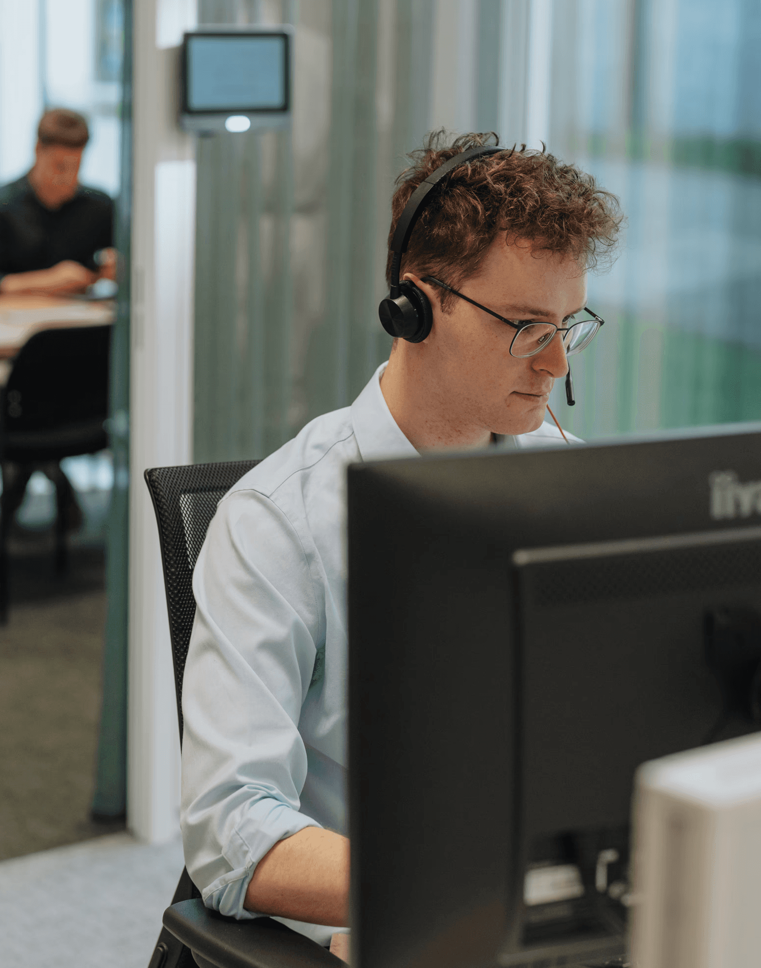 Professional at desk with computer, headset.