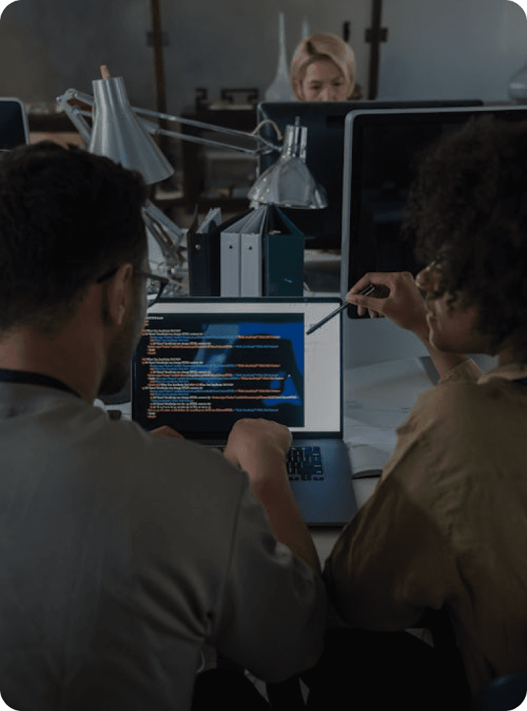 two persons looking at a laptop being used for coding