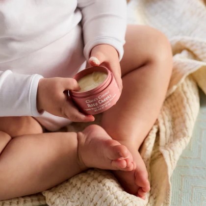 A lifestyle image featuring Clara's Corner Rosy Cheeks organic balm in a pink VIVOMER tub. The packaging offers a non-toxic and phthalate-free solution perfectly suited for child-friendly personal care brands.