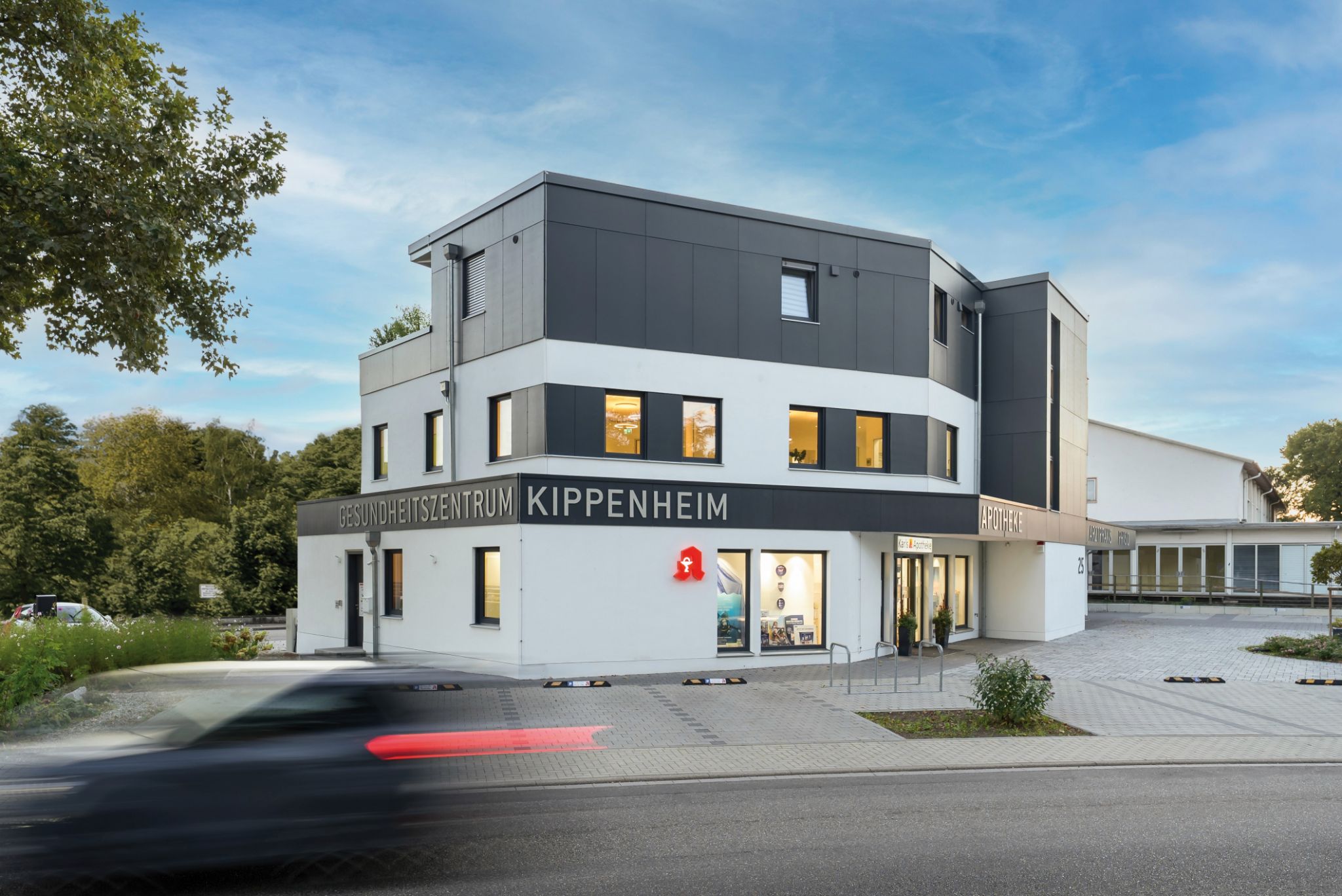 Modernes Gesundheitszentrum Kippenheim mit Apotheke und Arztpraxis, im Hintergrund Bäume und blauer Himmel.