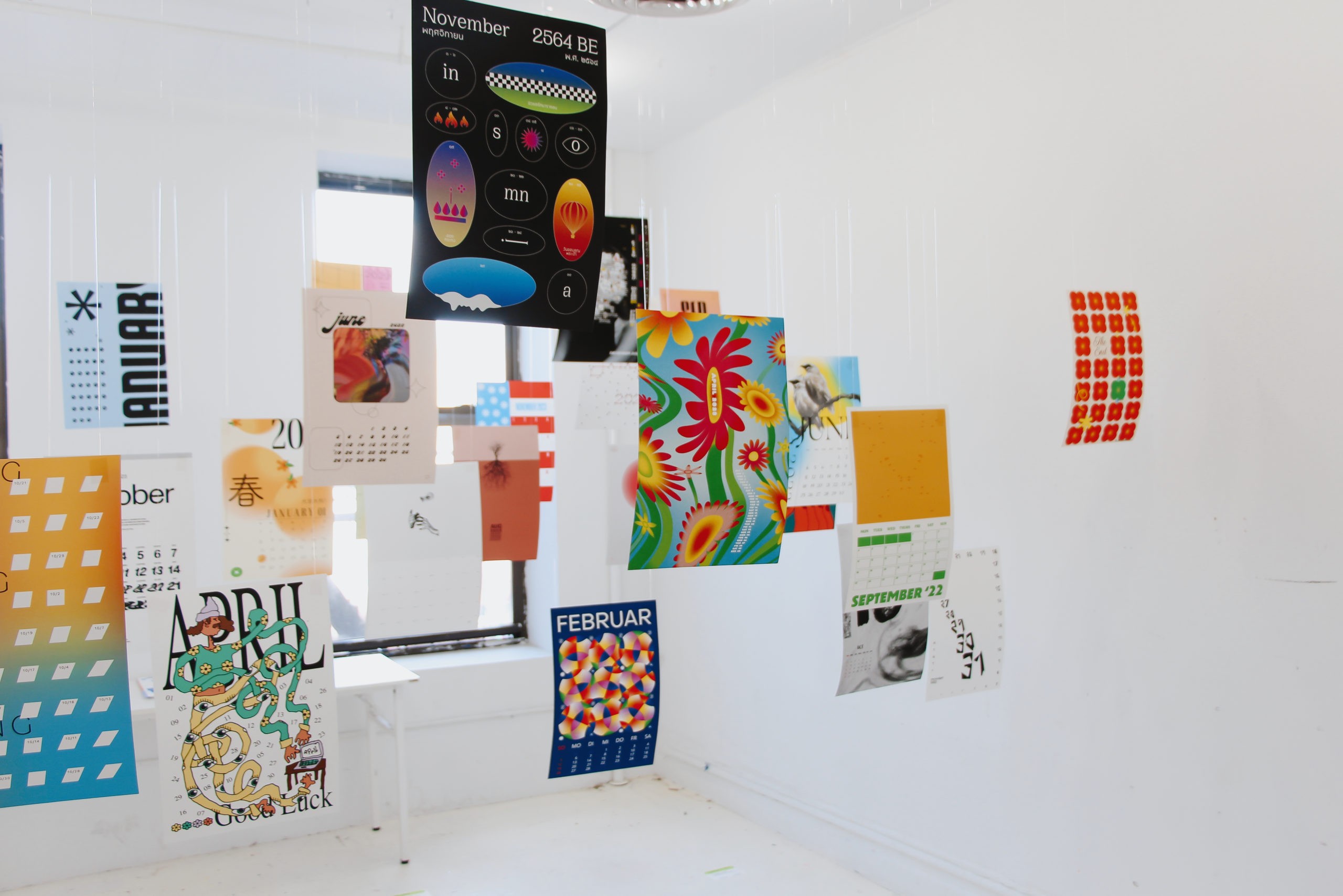Exhibition with multiple multi-colored posters hanging from the ceiling