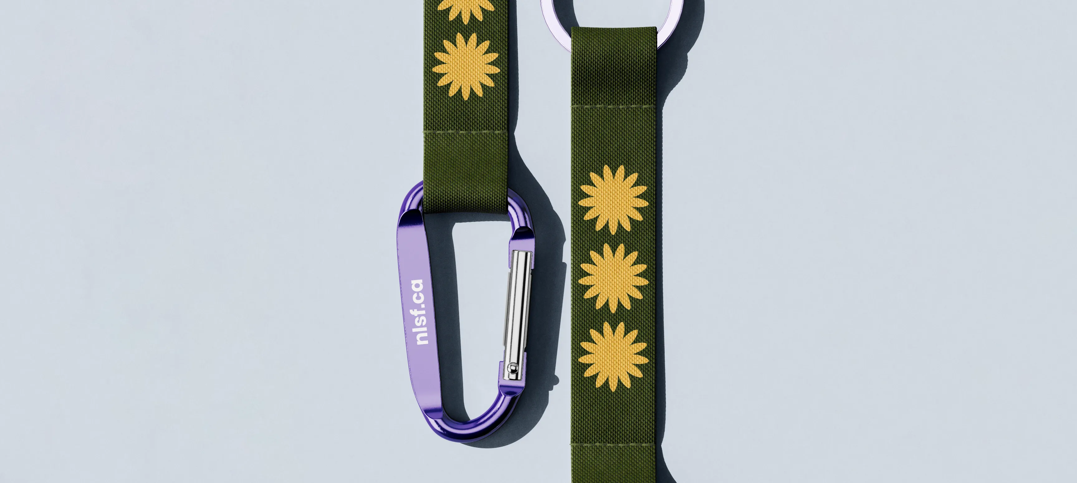 A carabiner keychain with a green strap with yellow flowers printed on it.
