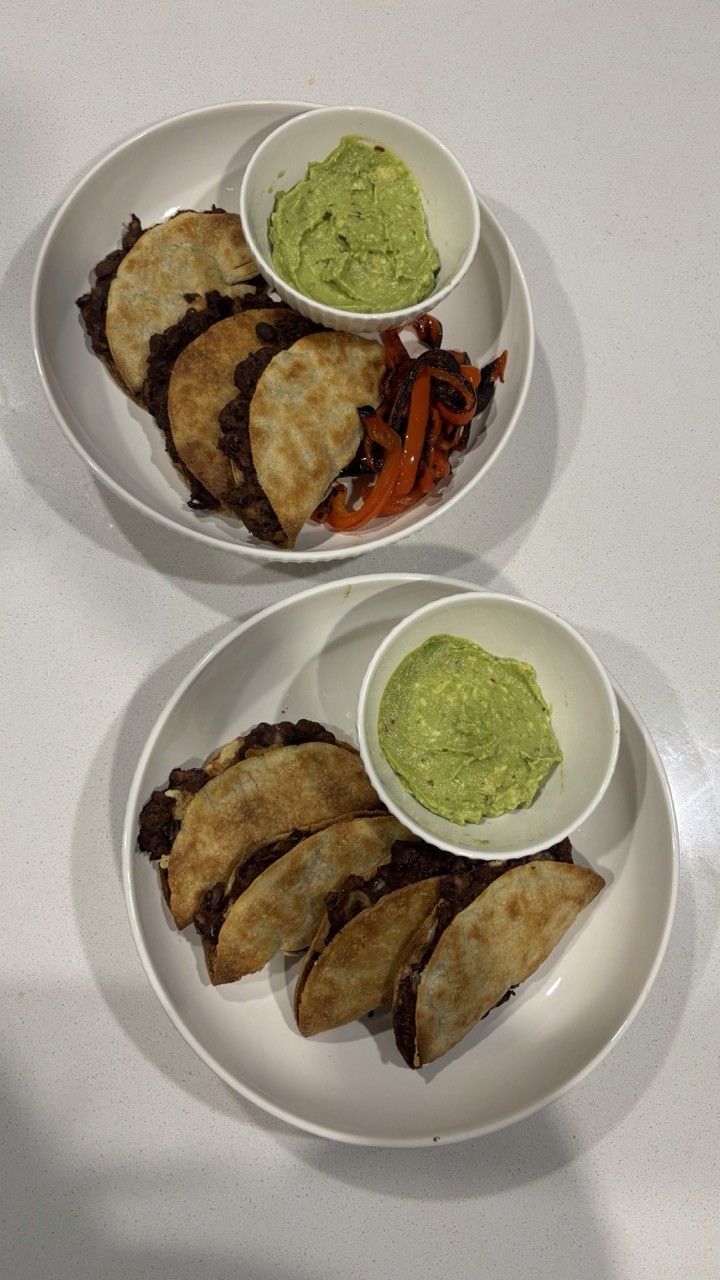 Two plates of crispy black bean tacos with guacamole and sautéed peppers – easy high protein taco night recipe Wellness by Suhey