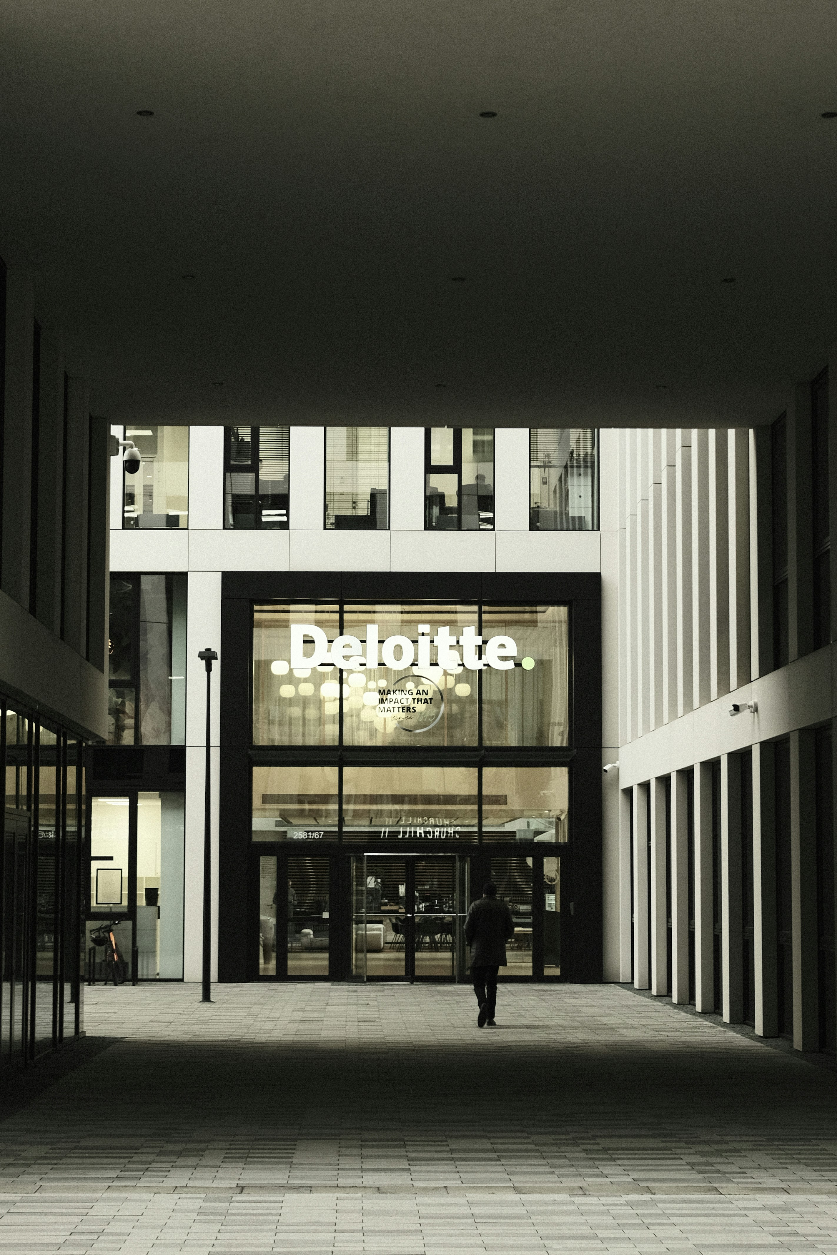 Man walks towards deloitte building entrance.
