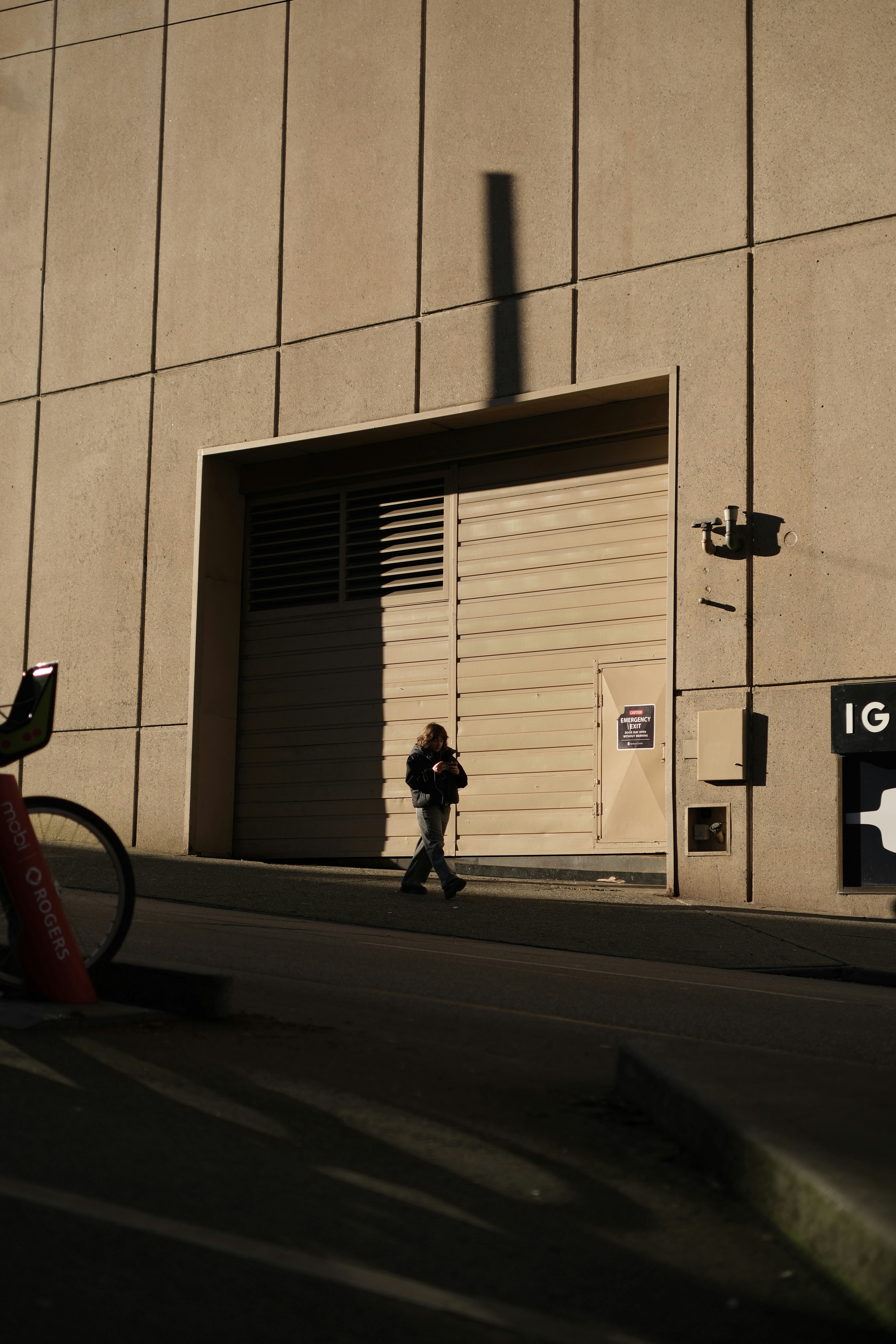 Person walks past a large open doorway with shadows.