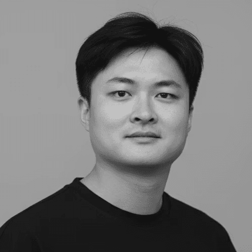 Portrait of a woman with straight long hair, in a dark t-shirt, set against a neutral backdrop.